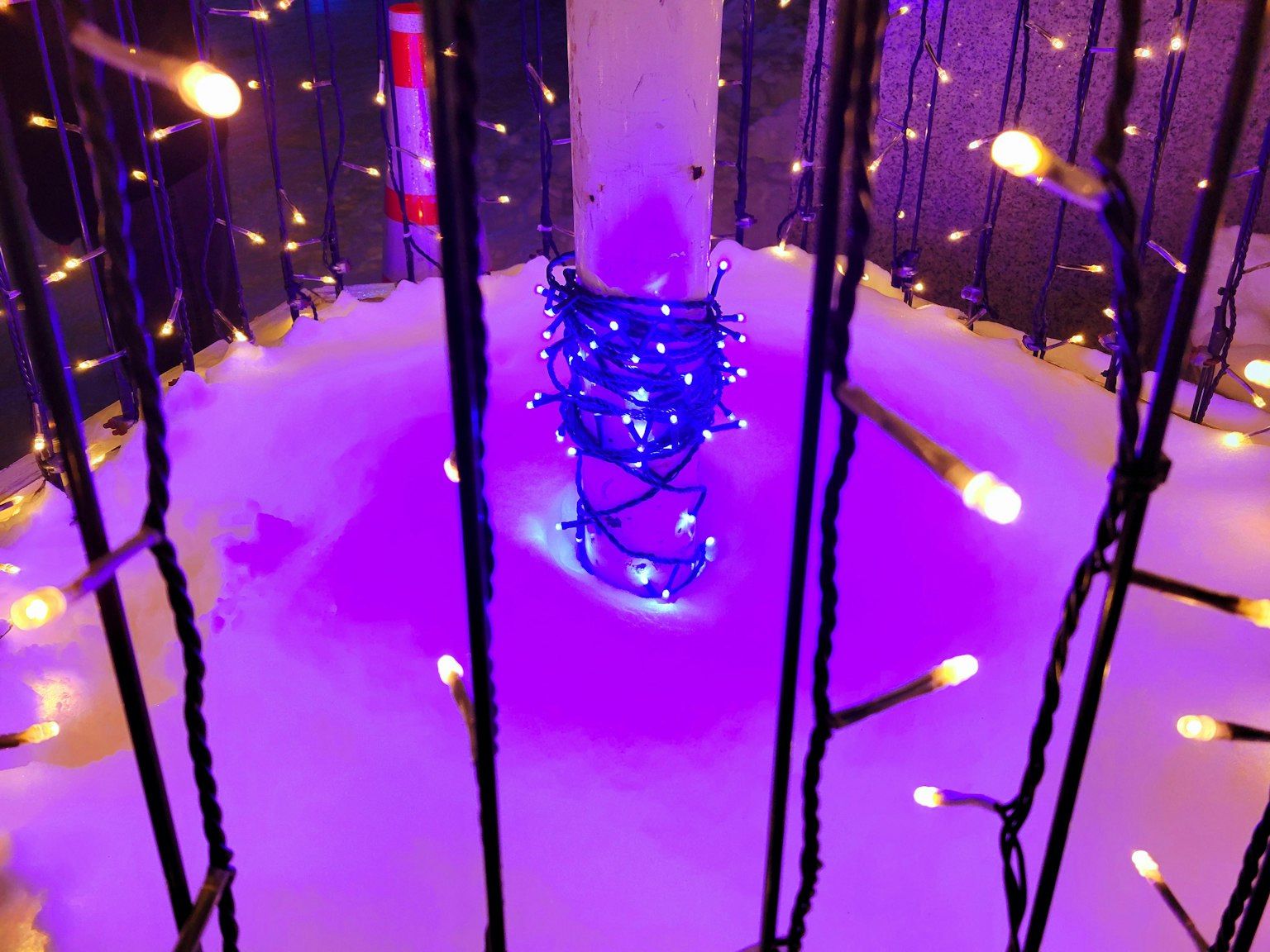 Un pilastro circondato da neve con luci decorative blu avvolte attorno