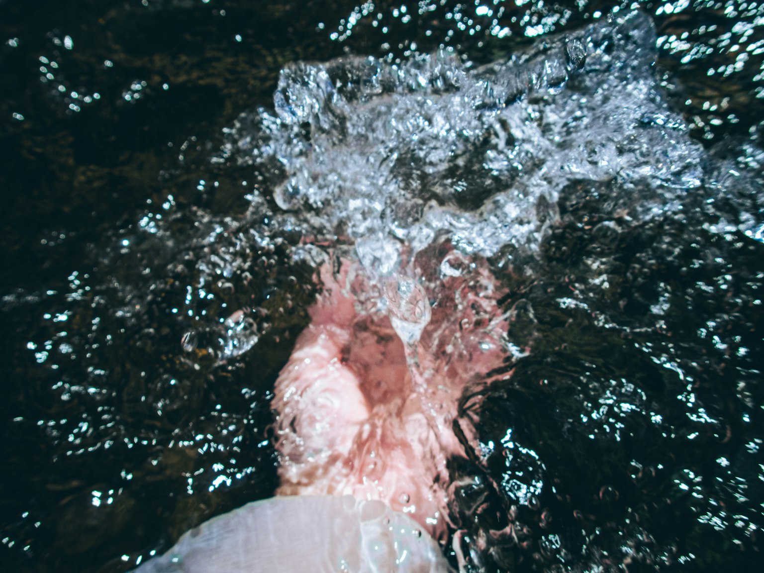 Immagine di una mano immersa nell'acqua con schizzi e bolle