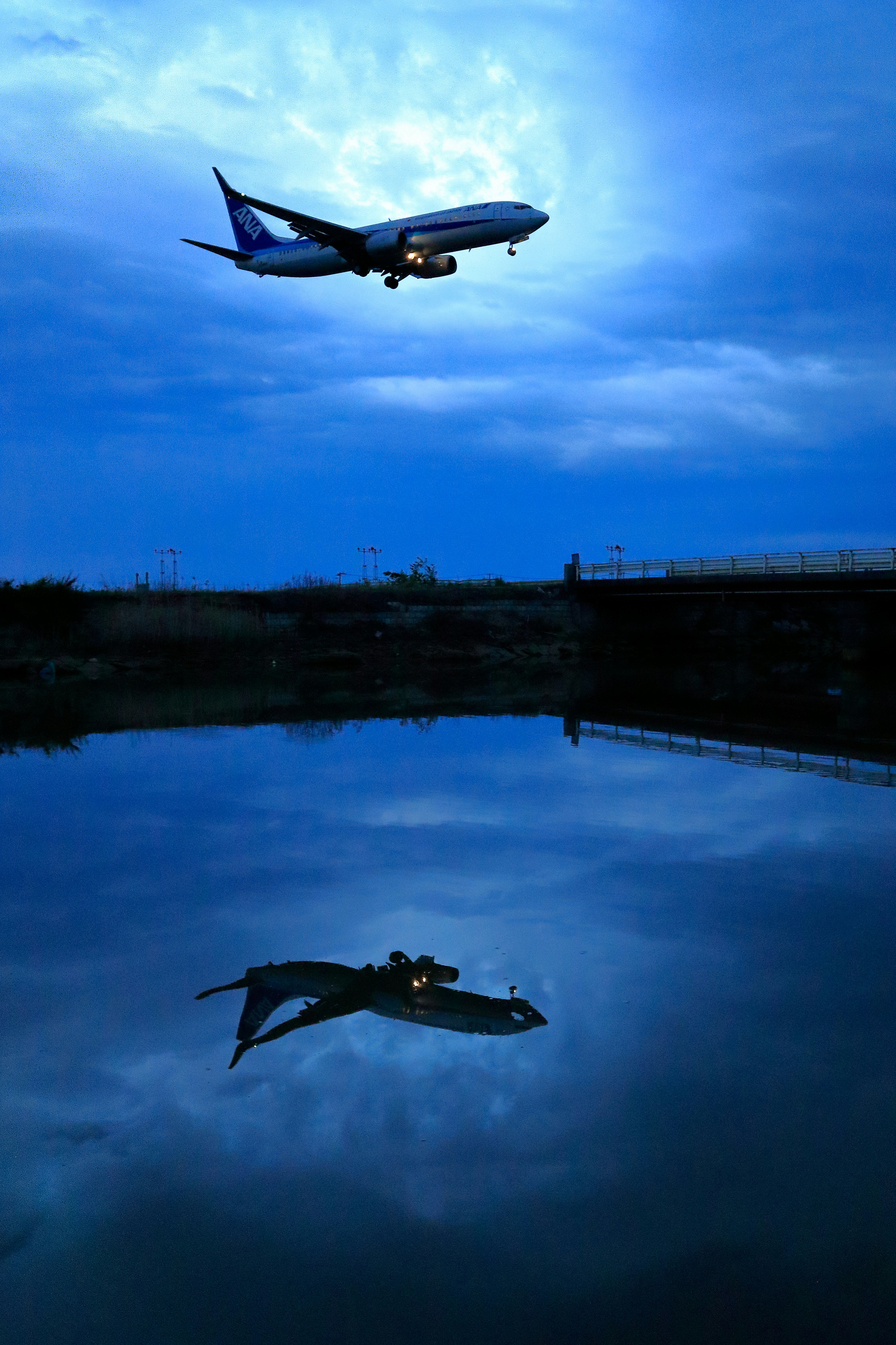 雨の夕暮れに水面へ映る飛行機のリフレクション