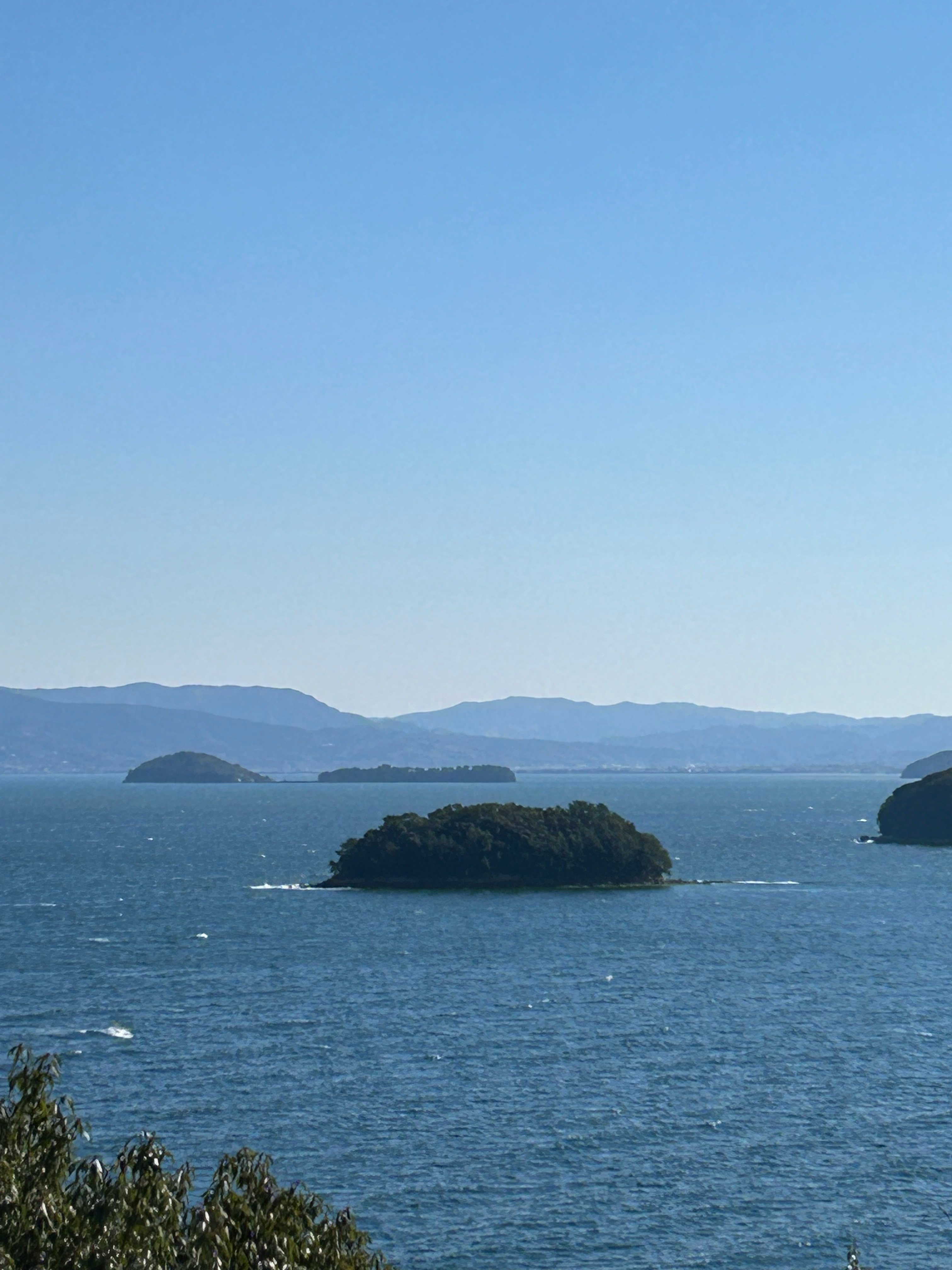 海に浮かぶ小島と遠くの山並みが見える海景
