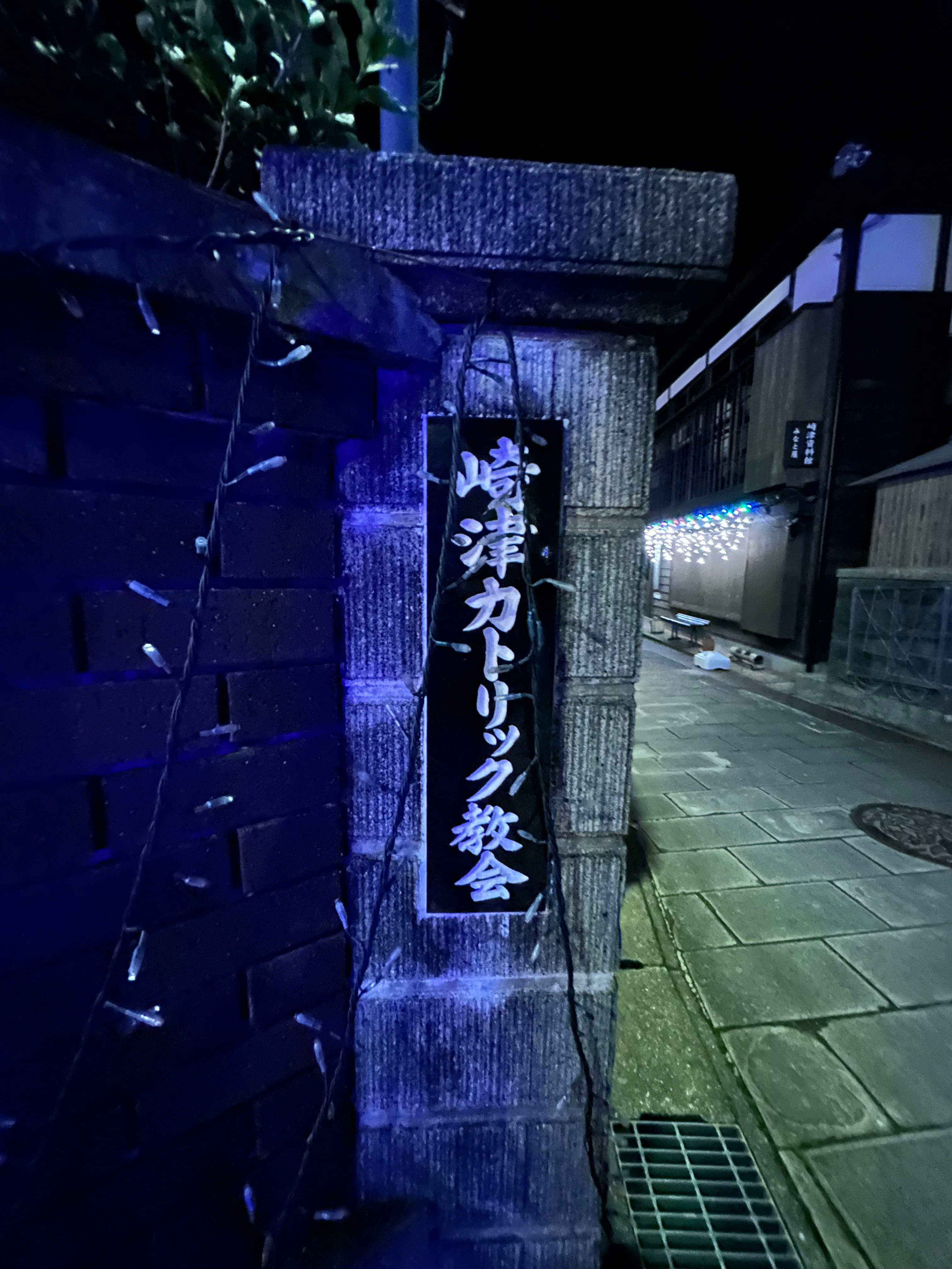 ruelle nocturne avec une enseigne et un mur en pierre