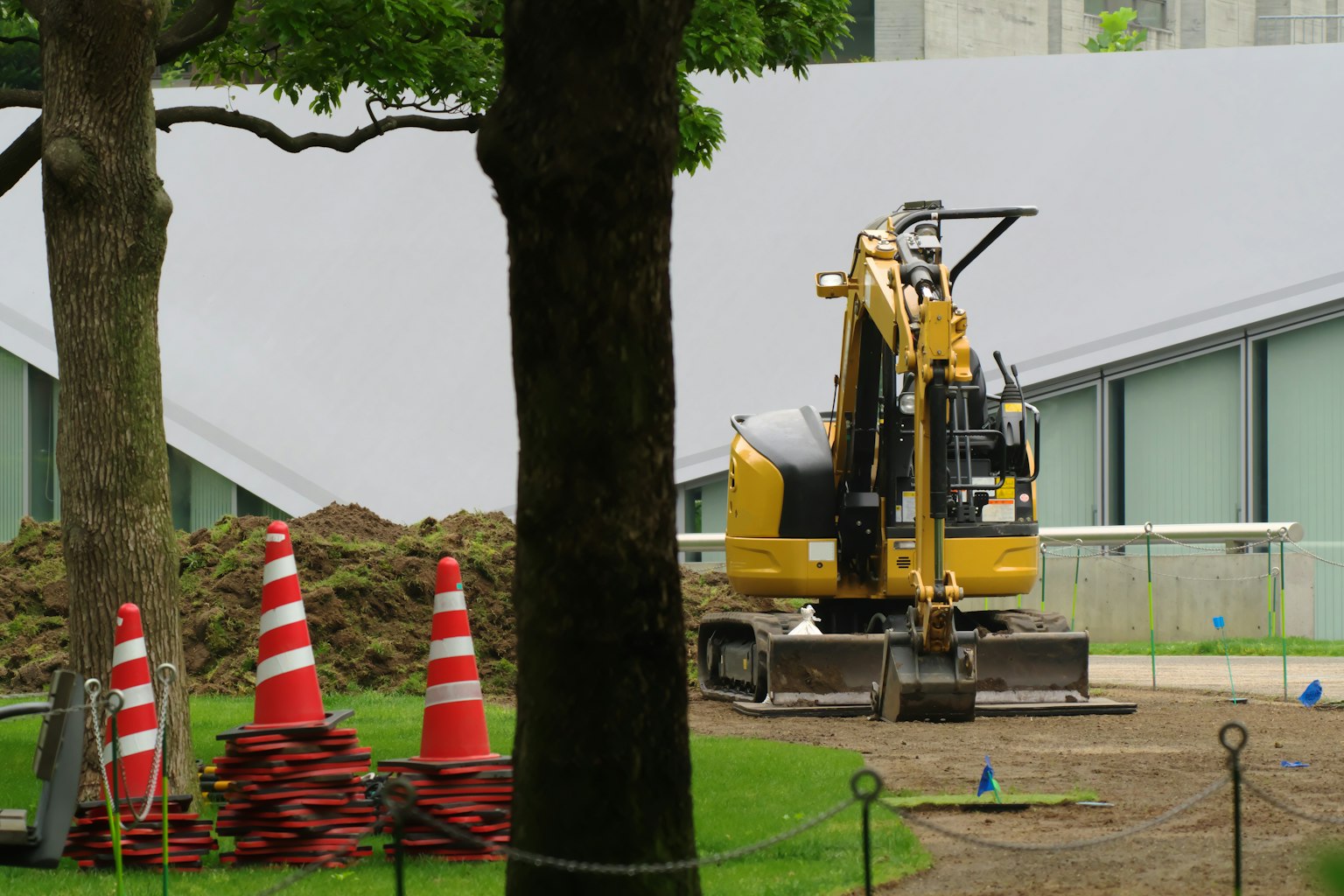 Construction scene featuring a yellow excavator and red traffic cones