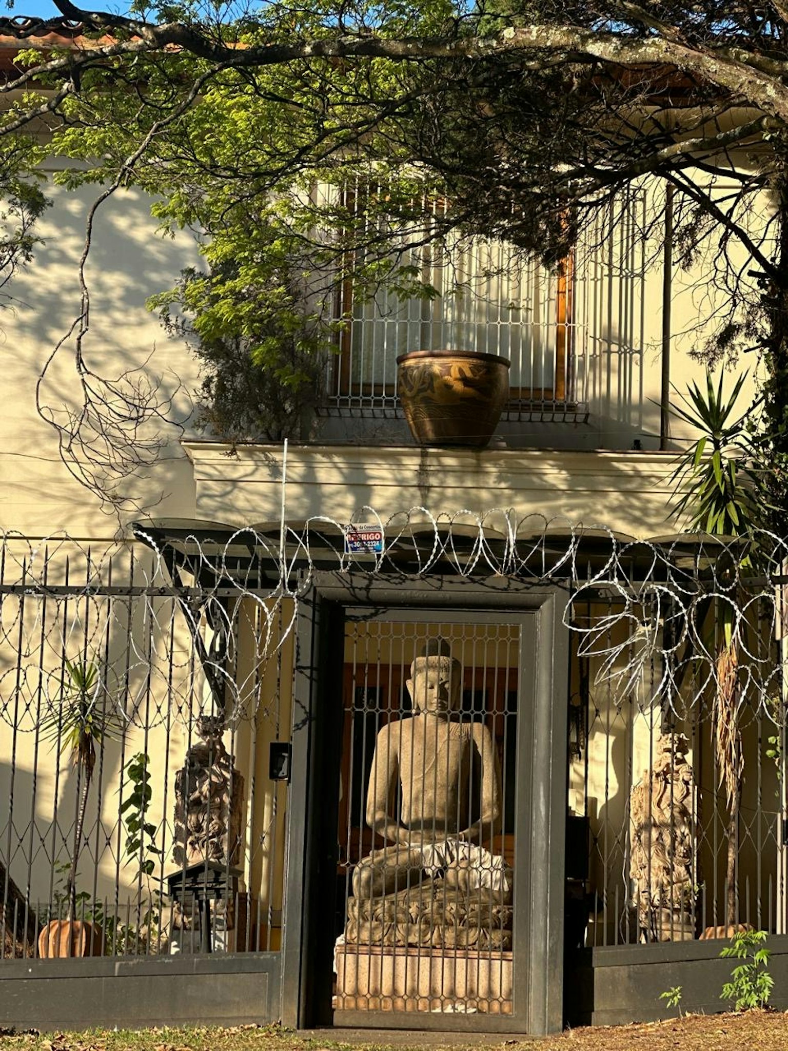 仏像が飾られた家の入口 植物と装飾的なフェンスが特徴