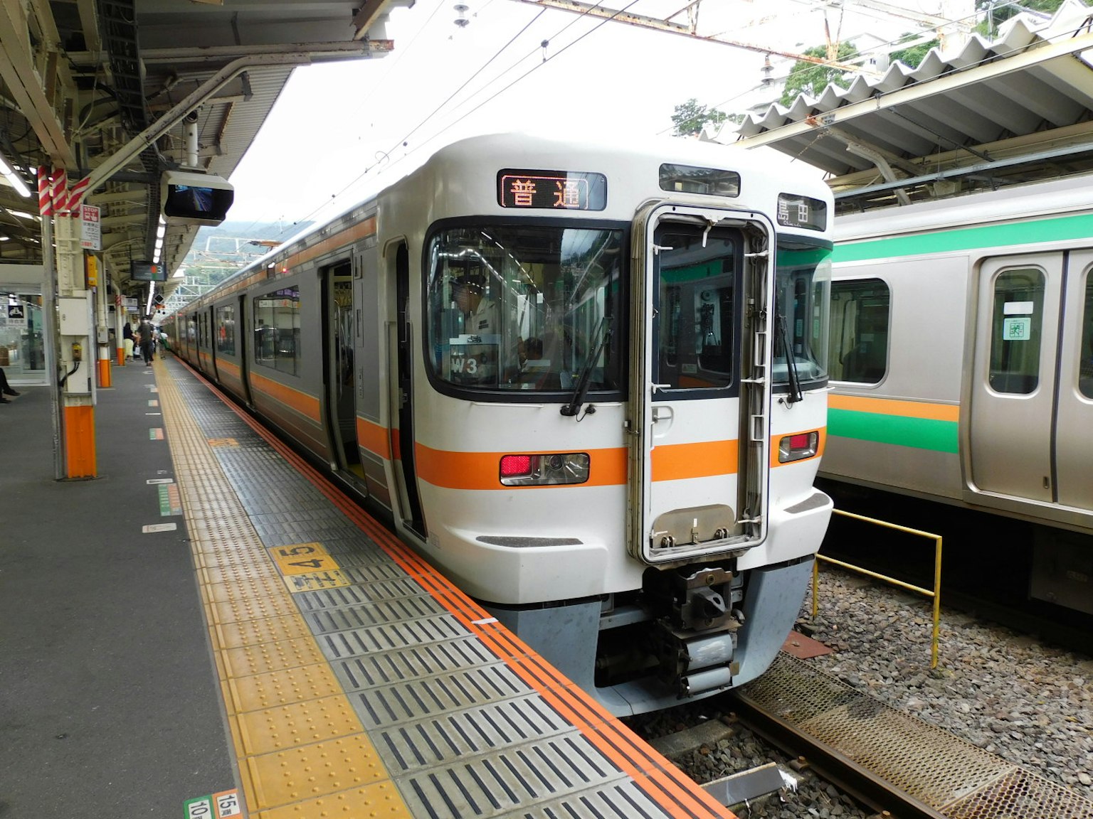 Japanese train with orange and white coloring at a station