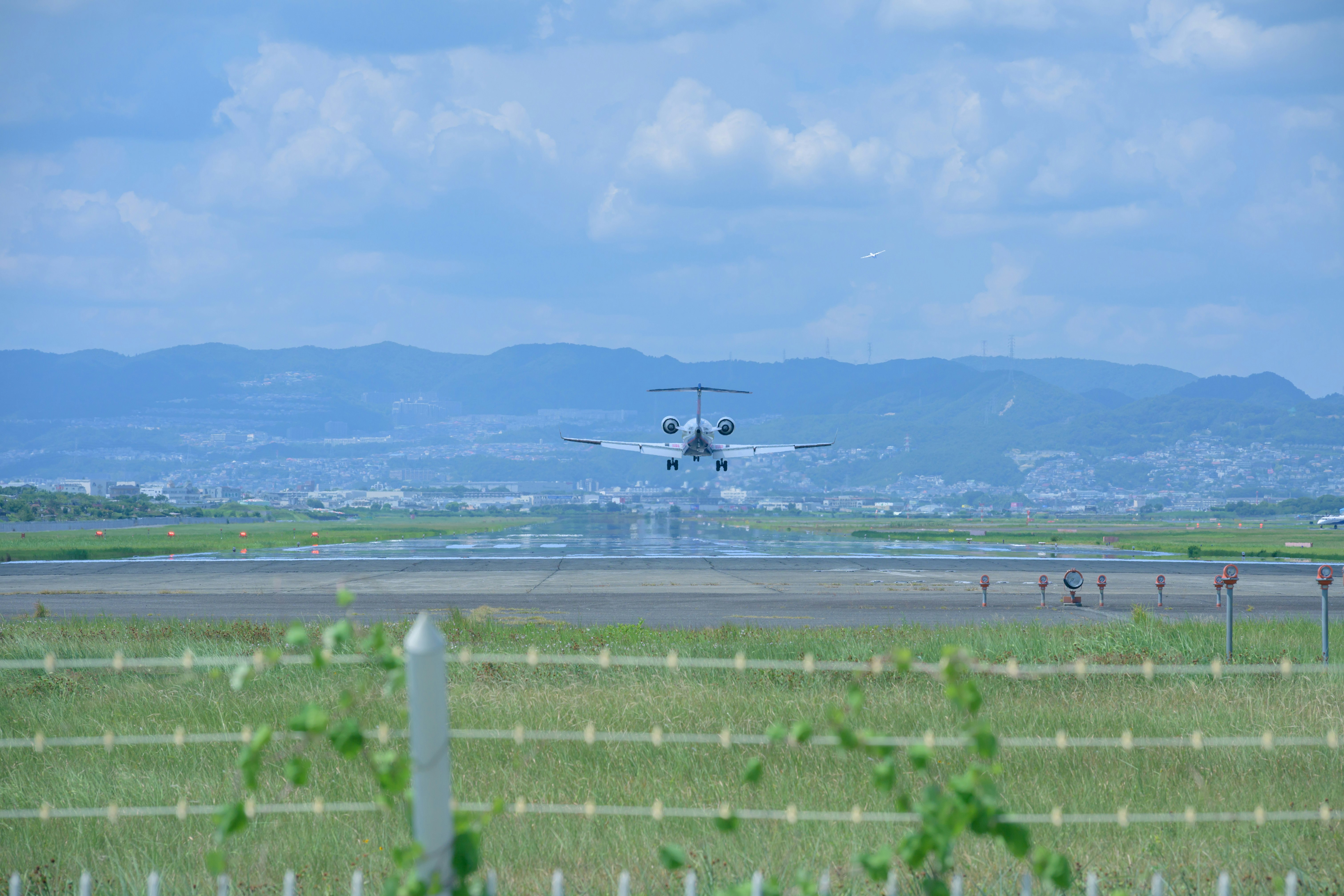 田園地帯を見下ろす飛行機と山並みの風景