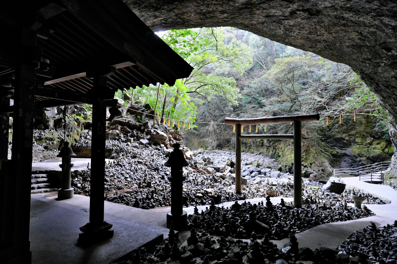 Scenic view of a shrine and torii gate inside a cave surrounded by nature