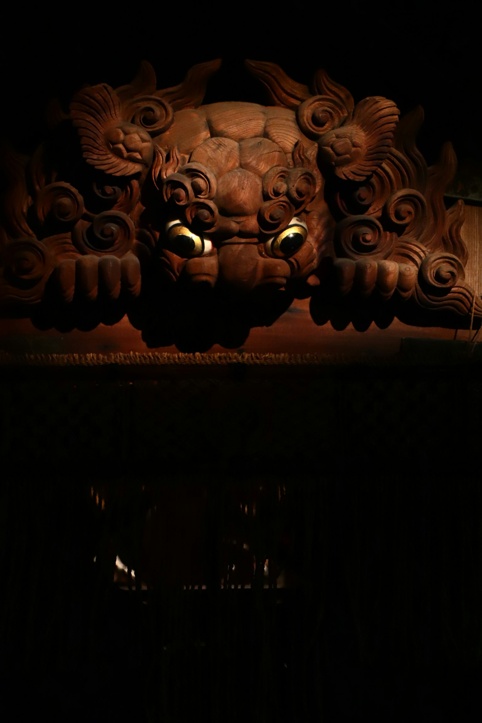 Scultura di testa di leone intagliata illuminata su sfondo scuro con occhi luminosi