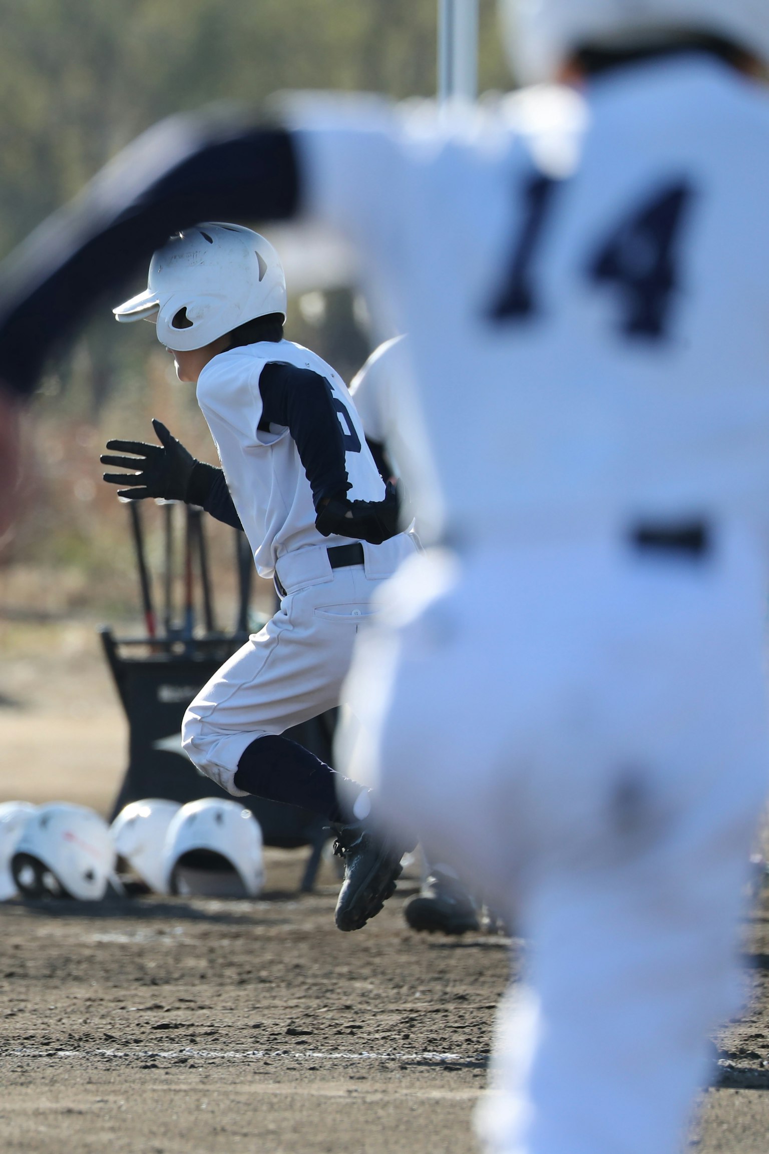Bambini in uniformi bianche che praticano il baseball su un campo