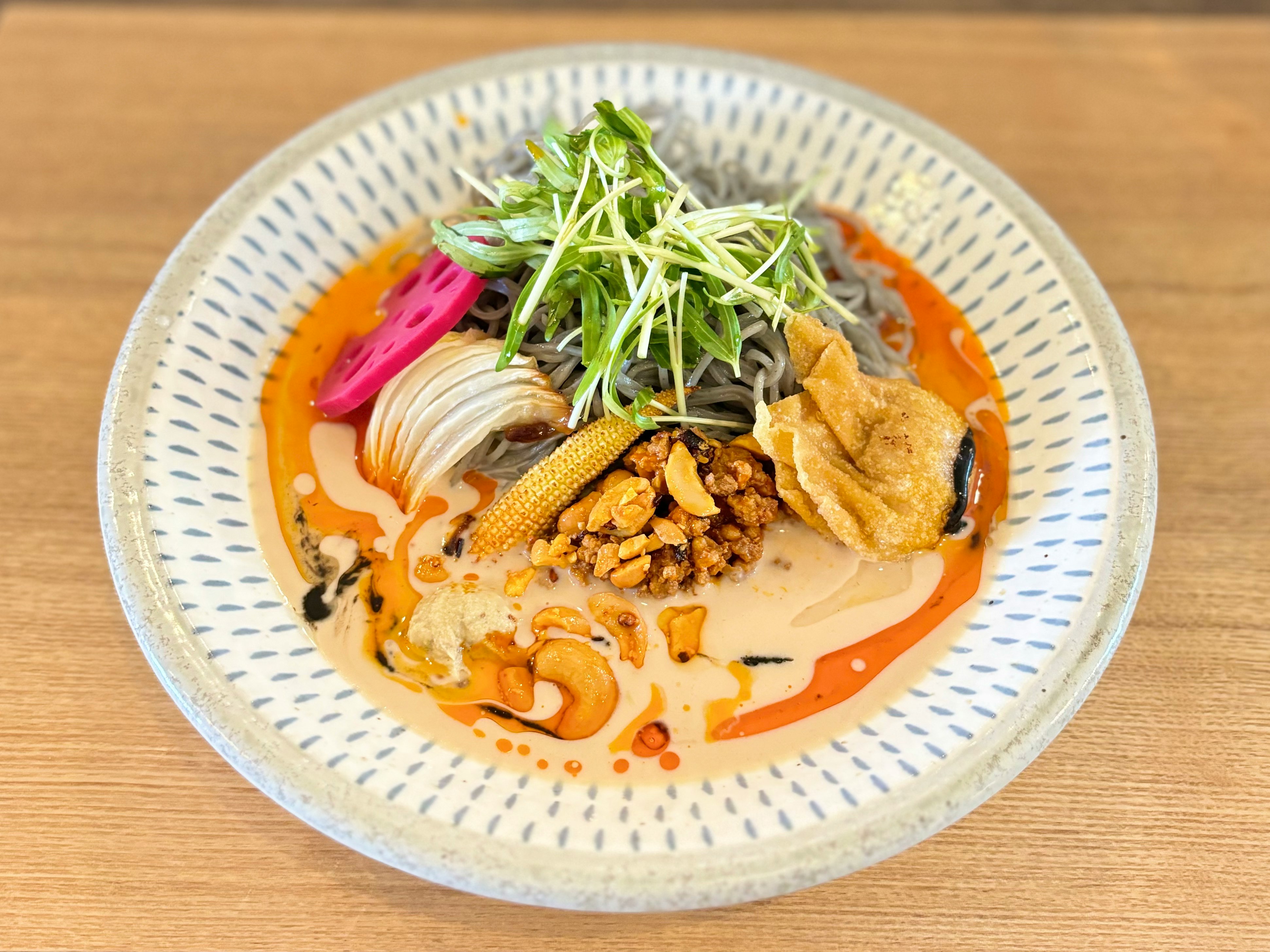 Primo piano di un piatto di noodles con ingredienti assortiti su salsa arancione