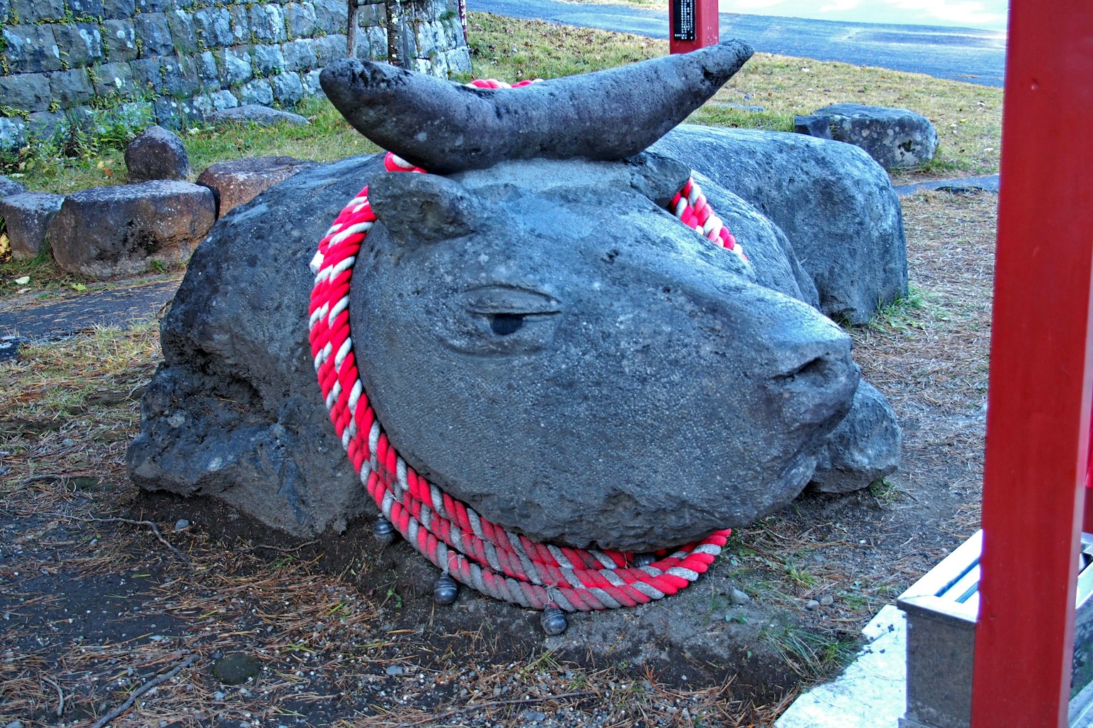 Scultura in pietra di una mucca decorata con una corda rossa e bianca
