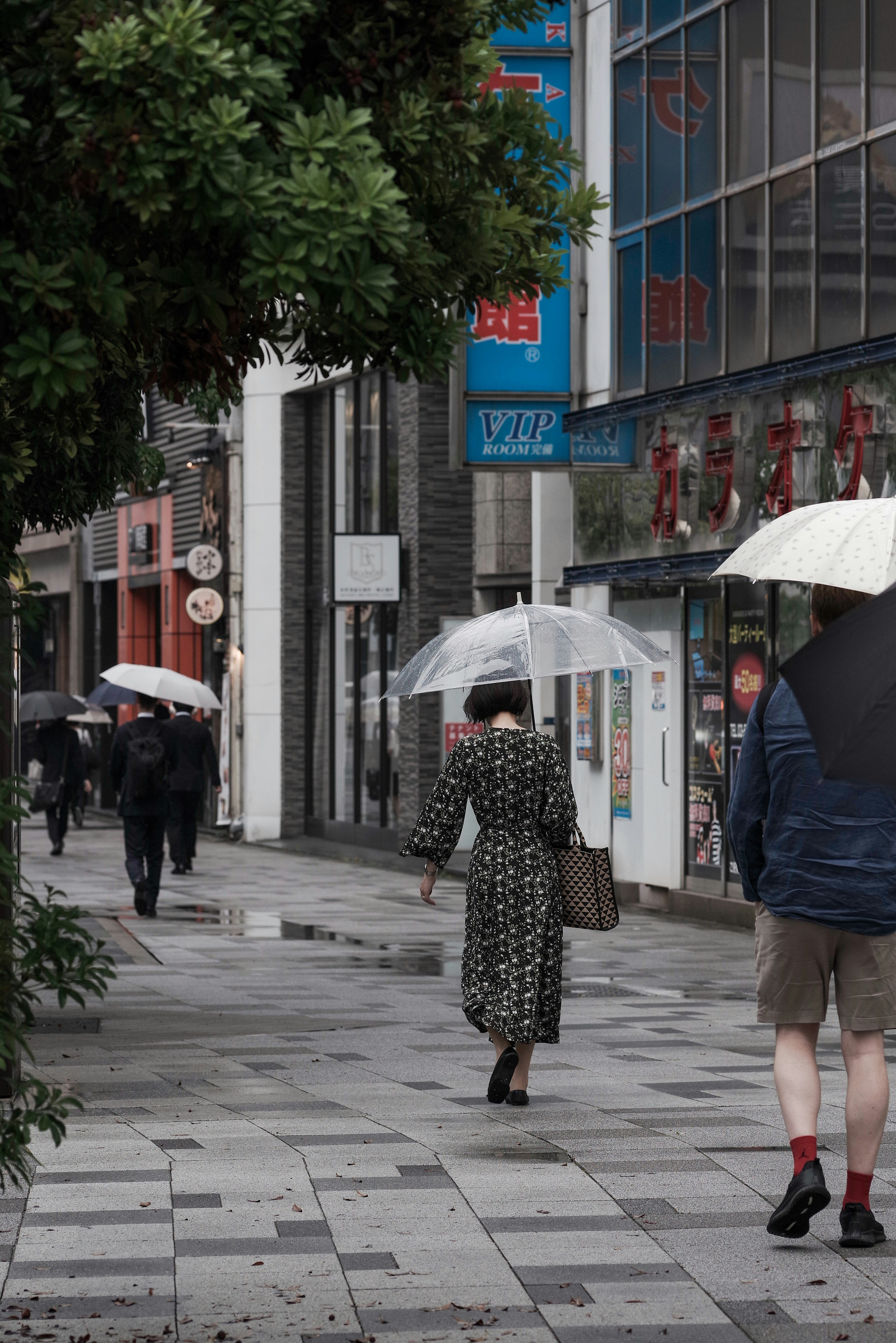 雨の日の街路で傘をさす人々の出勤風景