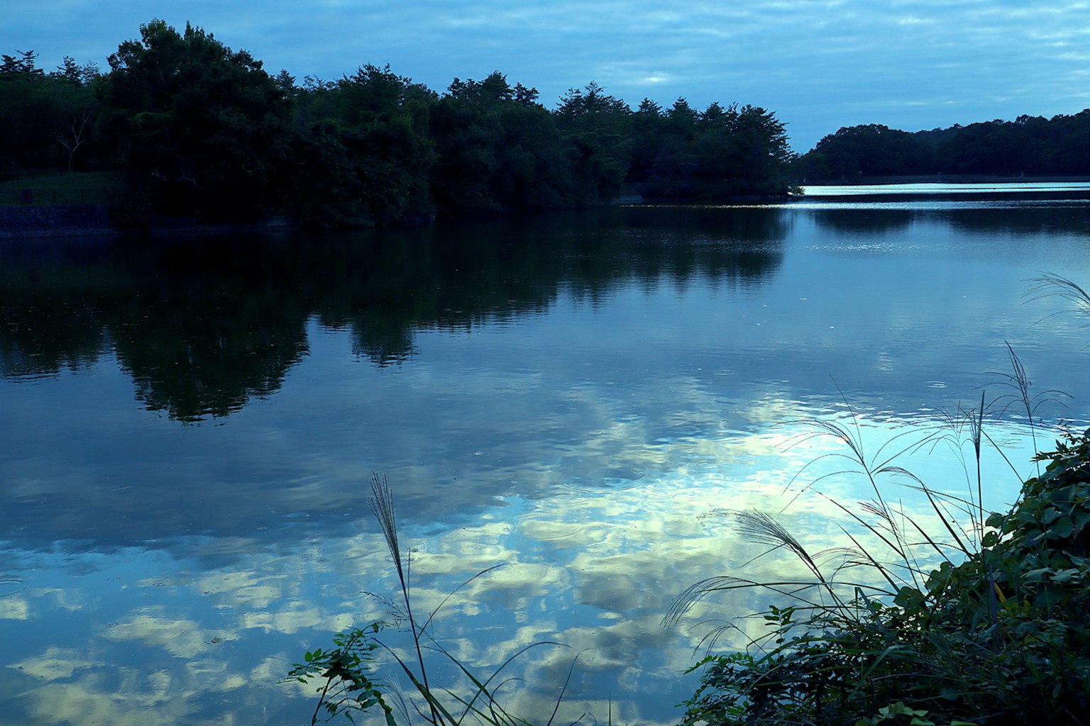 Ruhiger See, der den blauen Himmel und die Wolken spiegelt