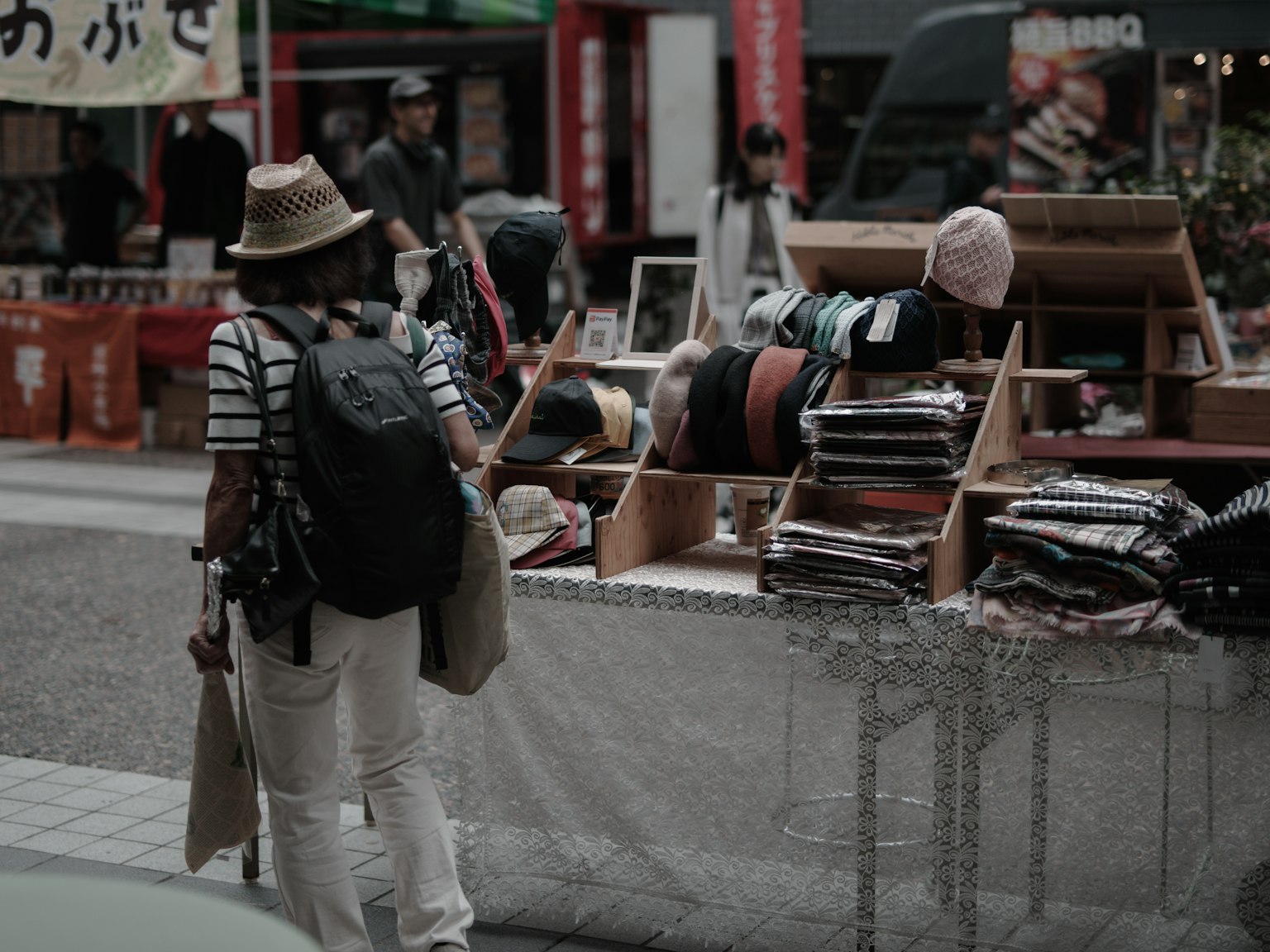 ผู้หญิงใส่หมวกกำลังดูสินค้าที่ตลาดถนน