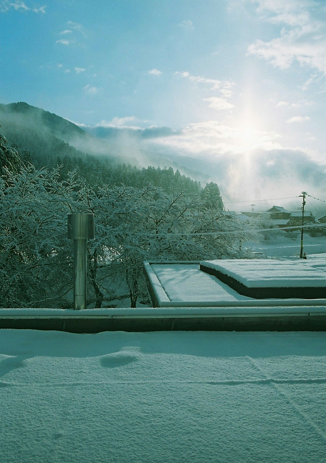 霧のかかった山並みを望む雪景色の屋外テラス