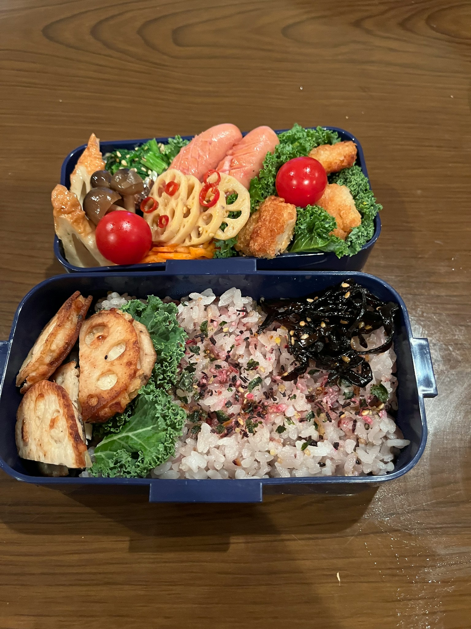 Bento dua tingkat yang lezat dengan salad, nasi, ikan, sayuran, dan tomat ceri