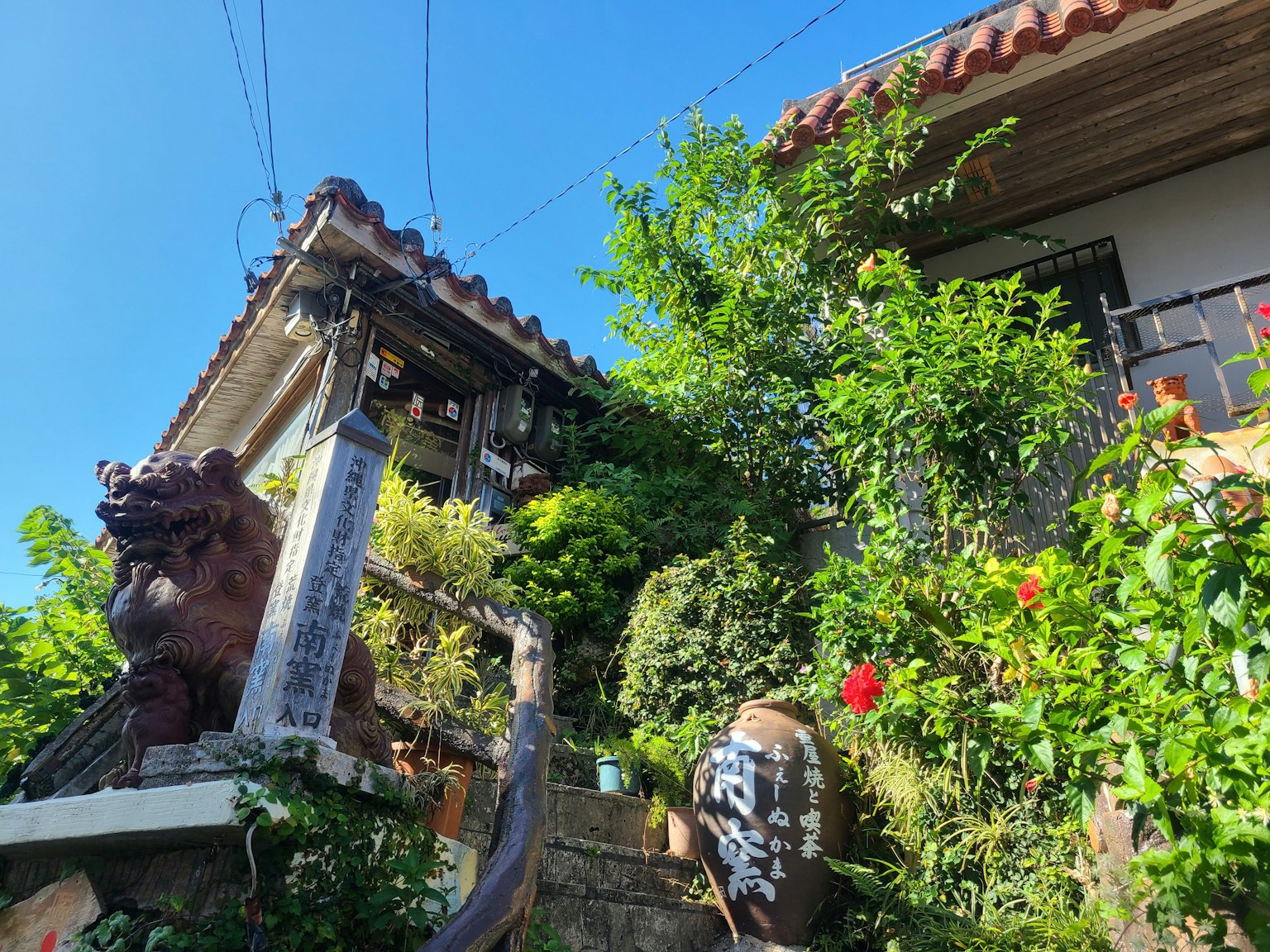 Maison traditionnelle entourée de verdure avec des escaliers et une sculpture de lion