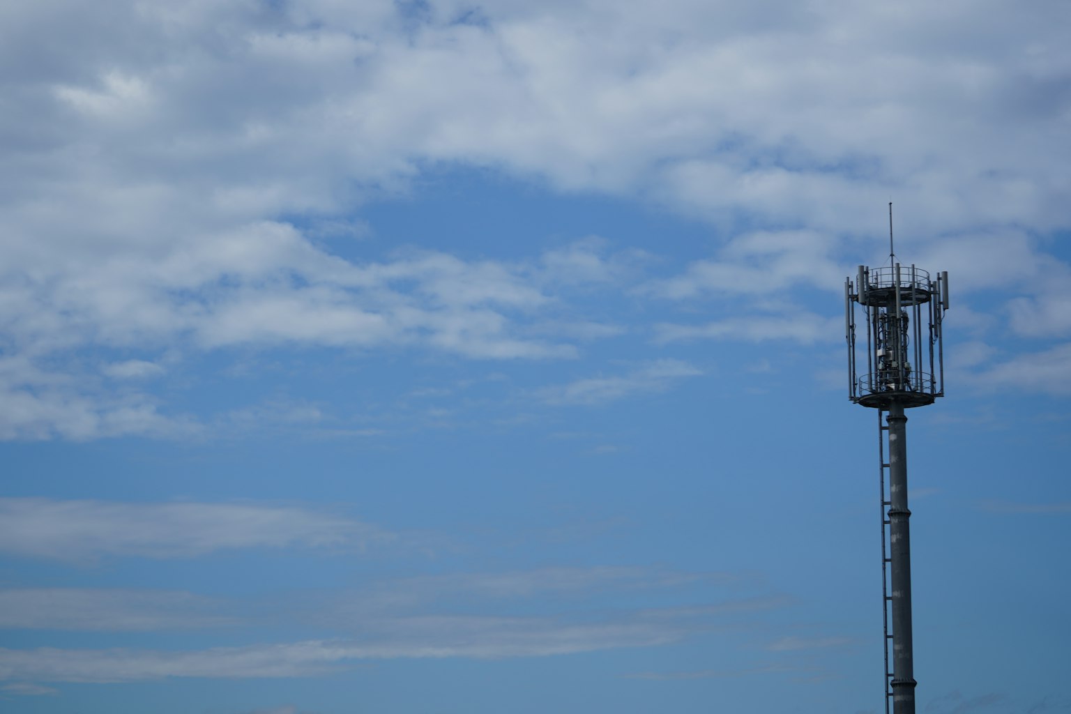 Menara komunikasi di bawah langit biru dengan awan