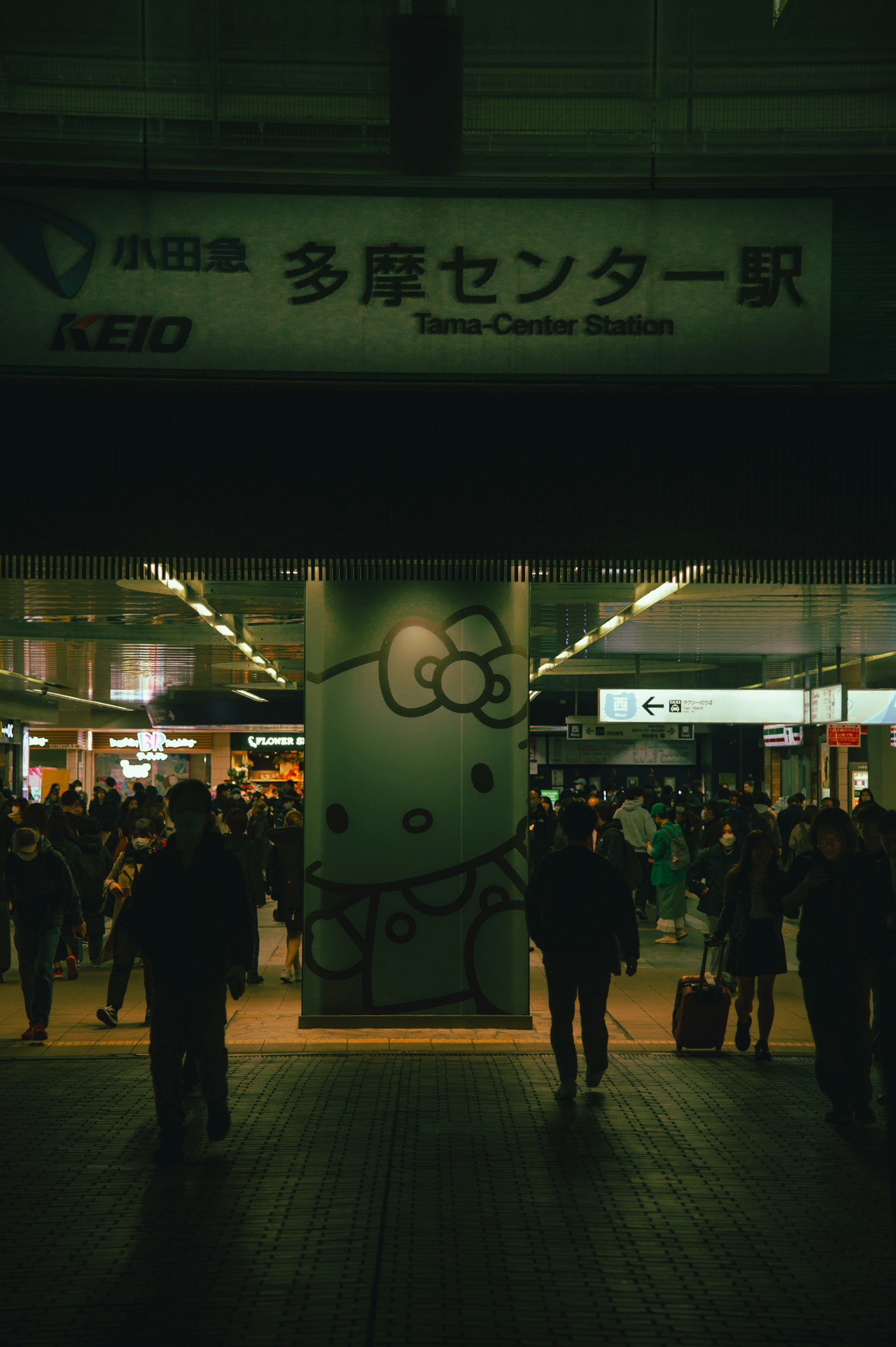 ป้ายสถานีทามะเซ็นเตอร์พร้อมภาพวาด Hello Kitty และผู้คนเดินผ่าน
