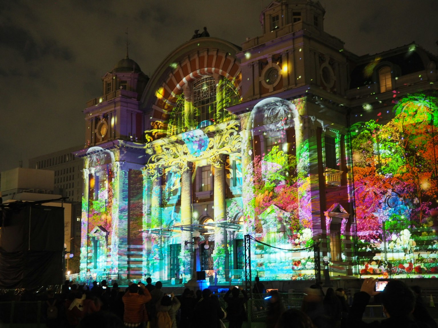Proiezione colorata su un edificio storico di notte con pubblico