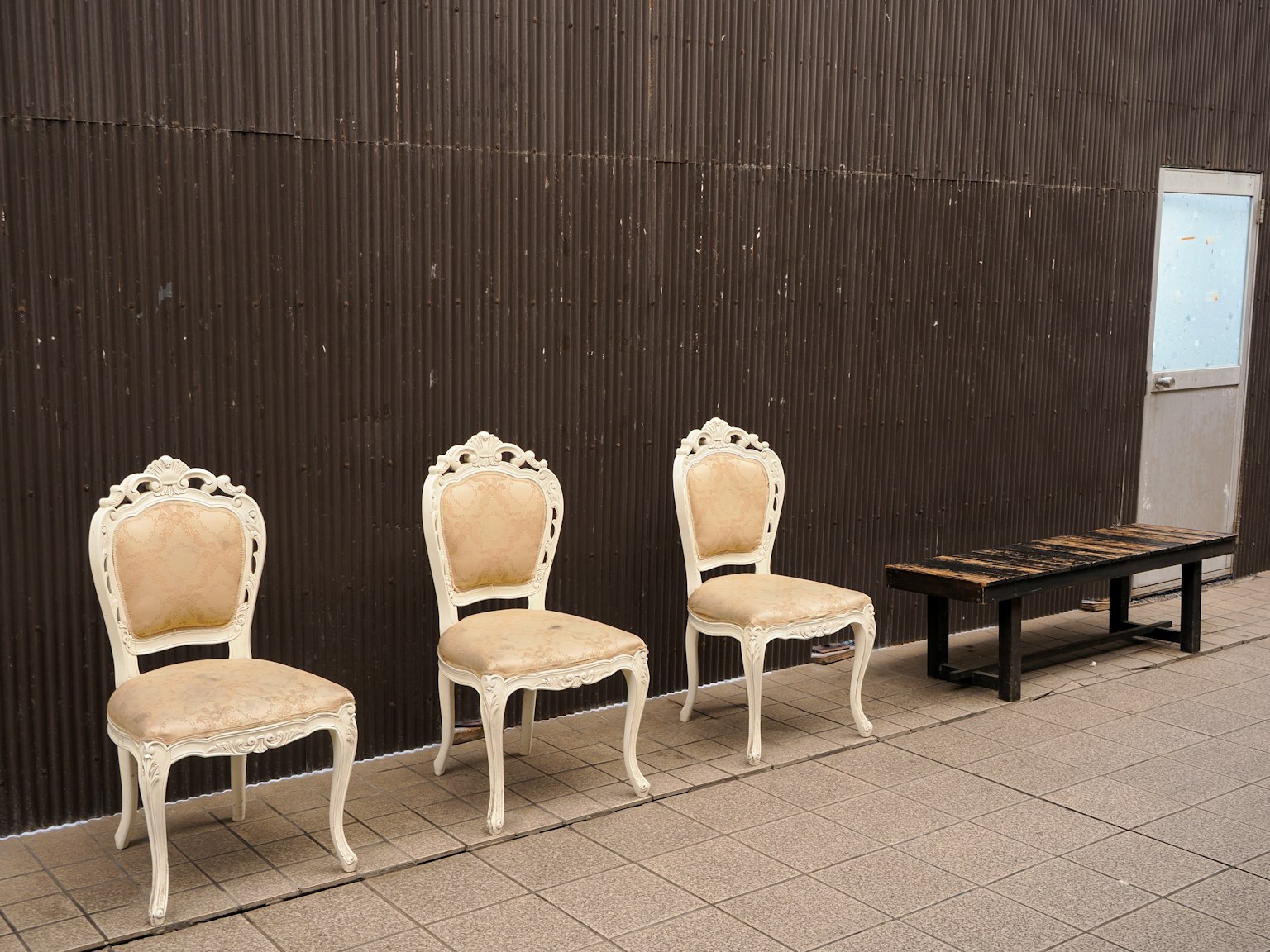 Drei verzierte weiße Stühle mit beigem Polster in einer minimalistischen Umgebung angeordnet