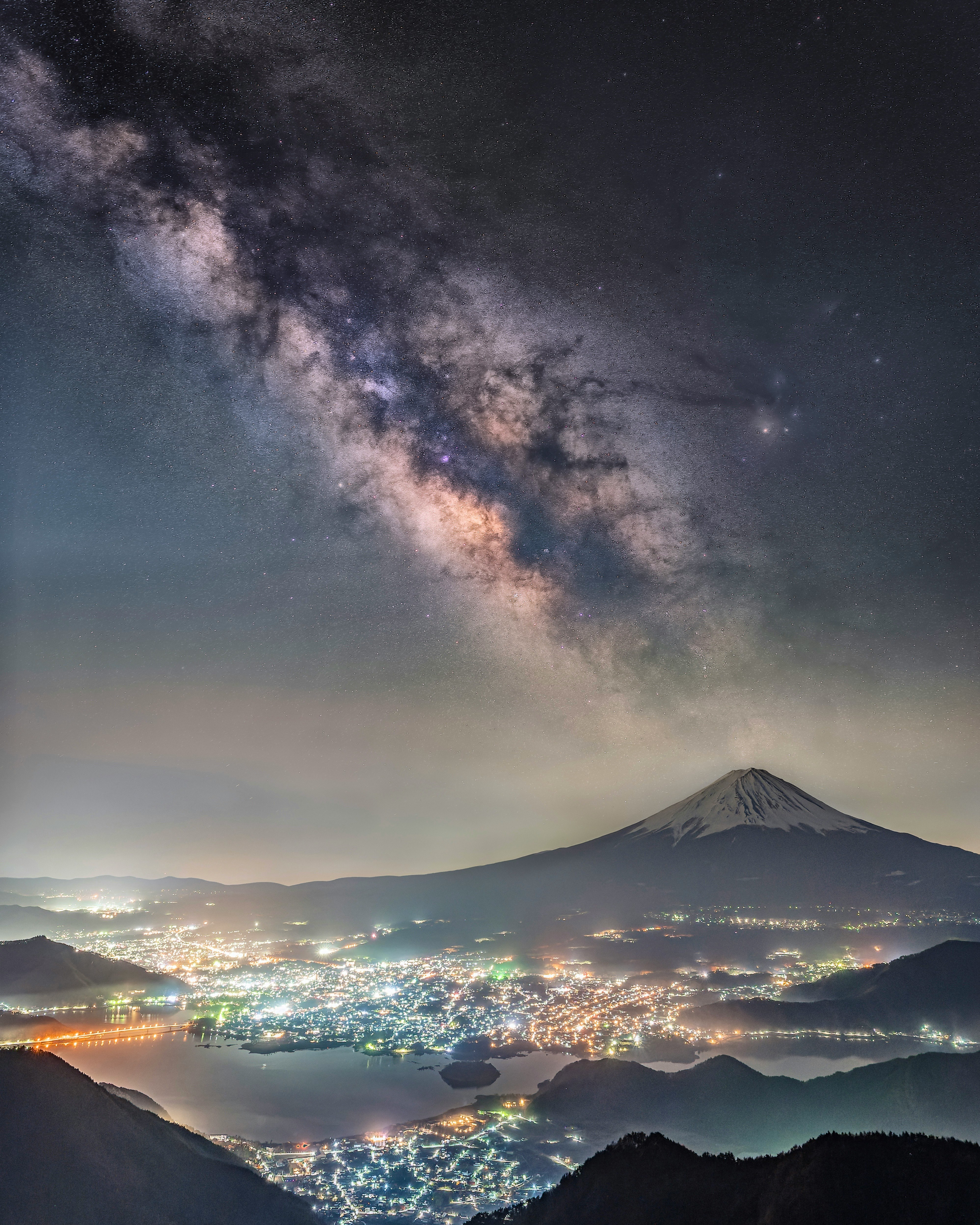 cordillera con ciudad nocturna y Vía Láctea