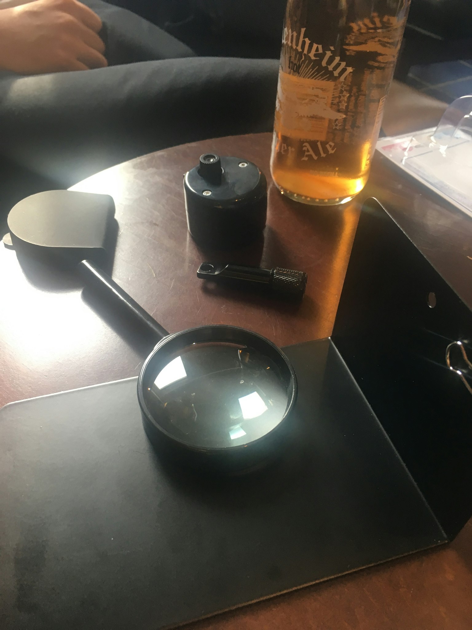 Lupe und Bierflasche auf einem Tisch