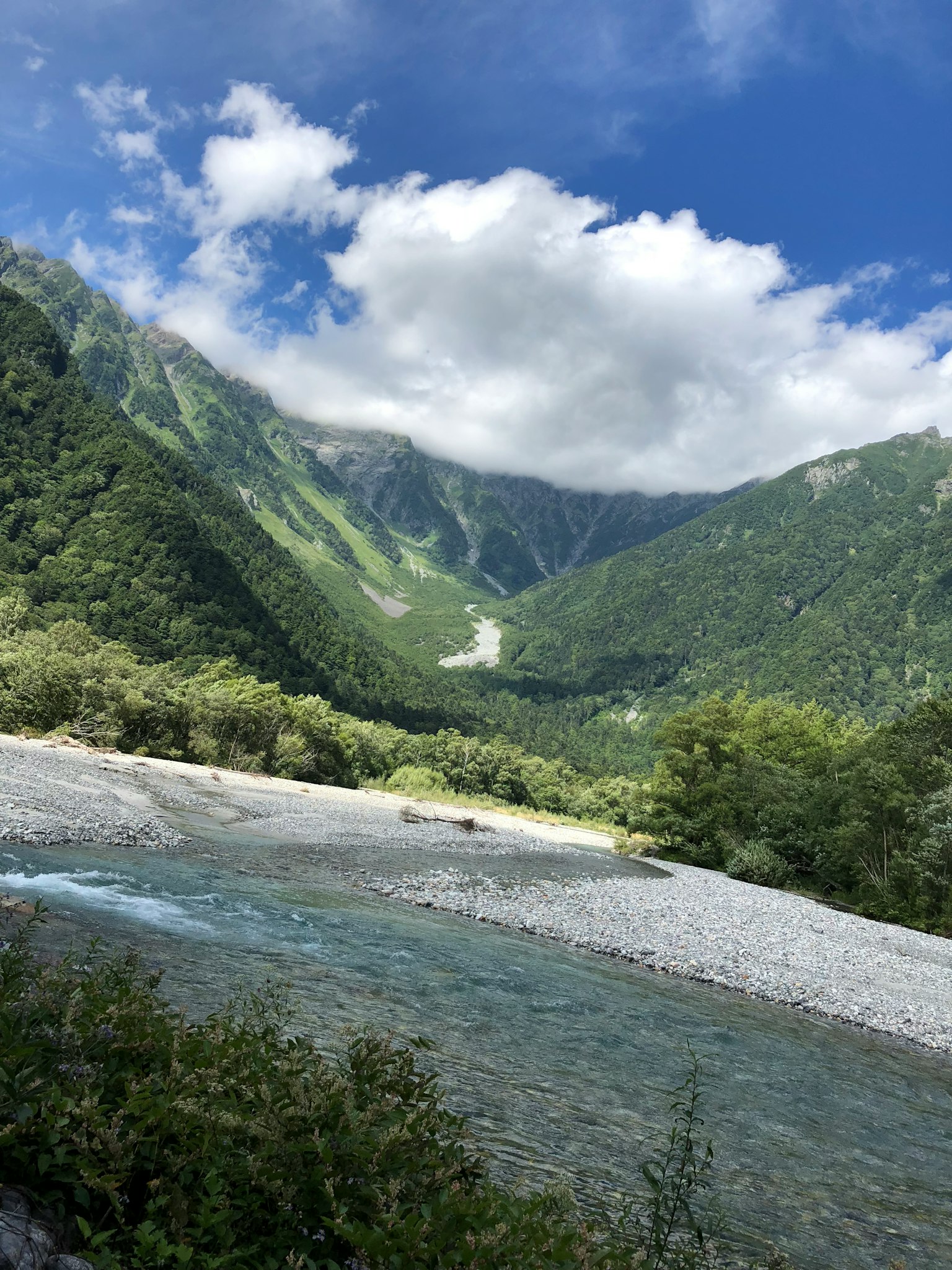 青翠山脉和河流在明亮天空下的风景