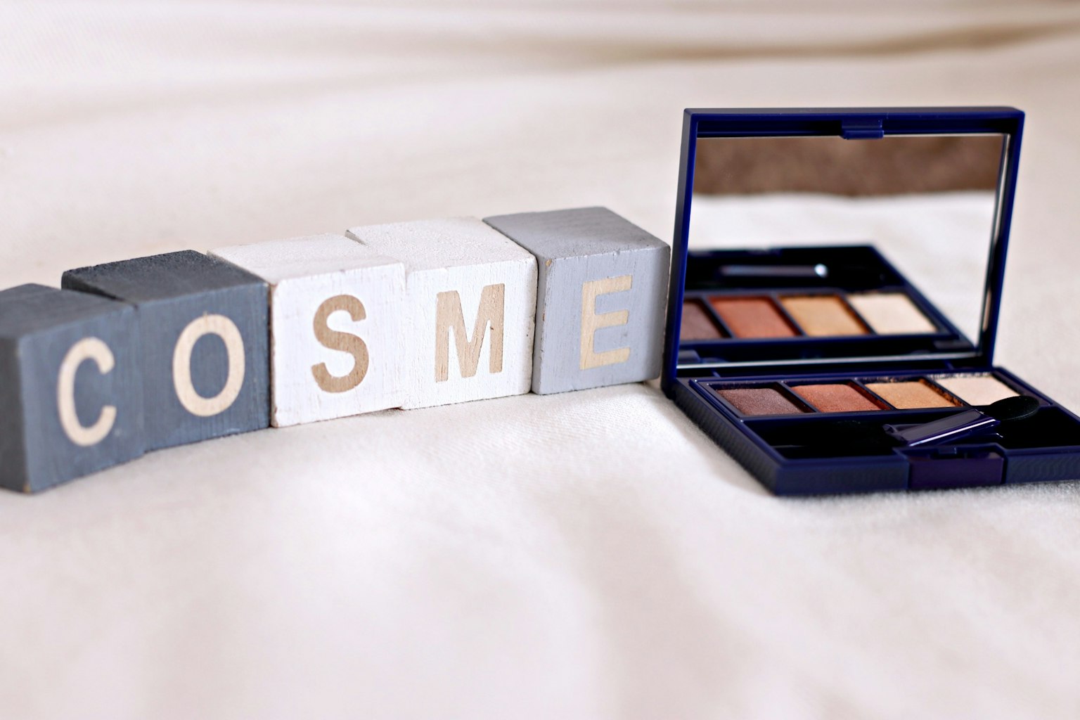 化妆品调色板旁边拼写COSME的积木