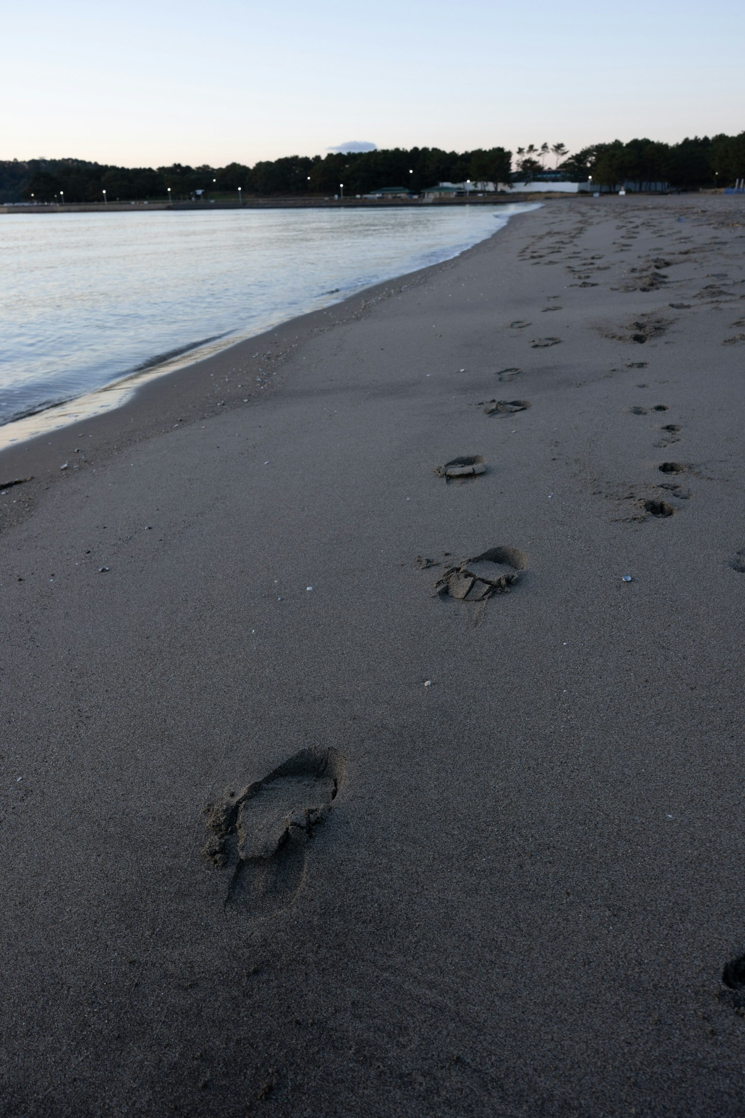 Impronte sulla spiaggia di sabbia con acqua calma sullo sfondo