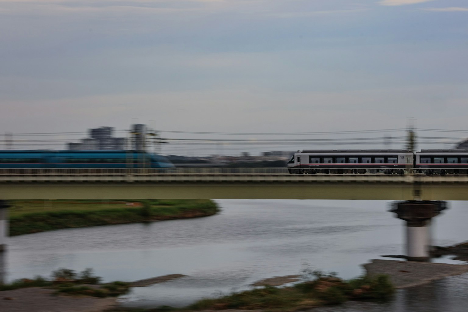 Train crossing a bridge with a river view