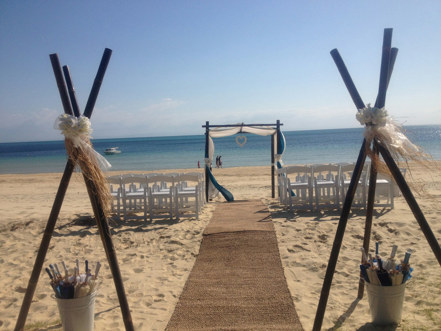 Hochzeitsaufbau am Strand mit weißen Stühlen und blauem Ozean