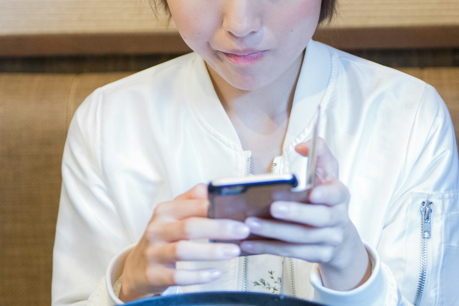 一名女性坐在桌子旁使用智能手机