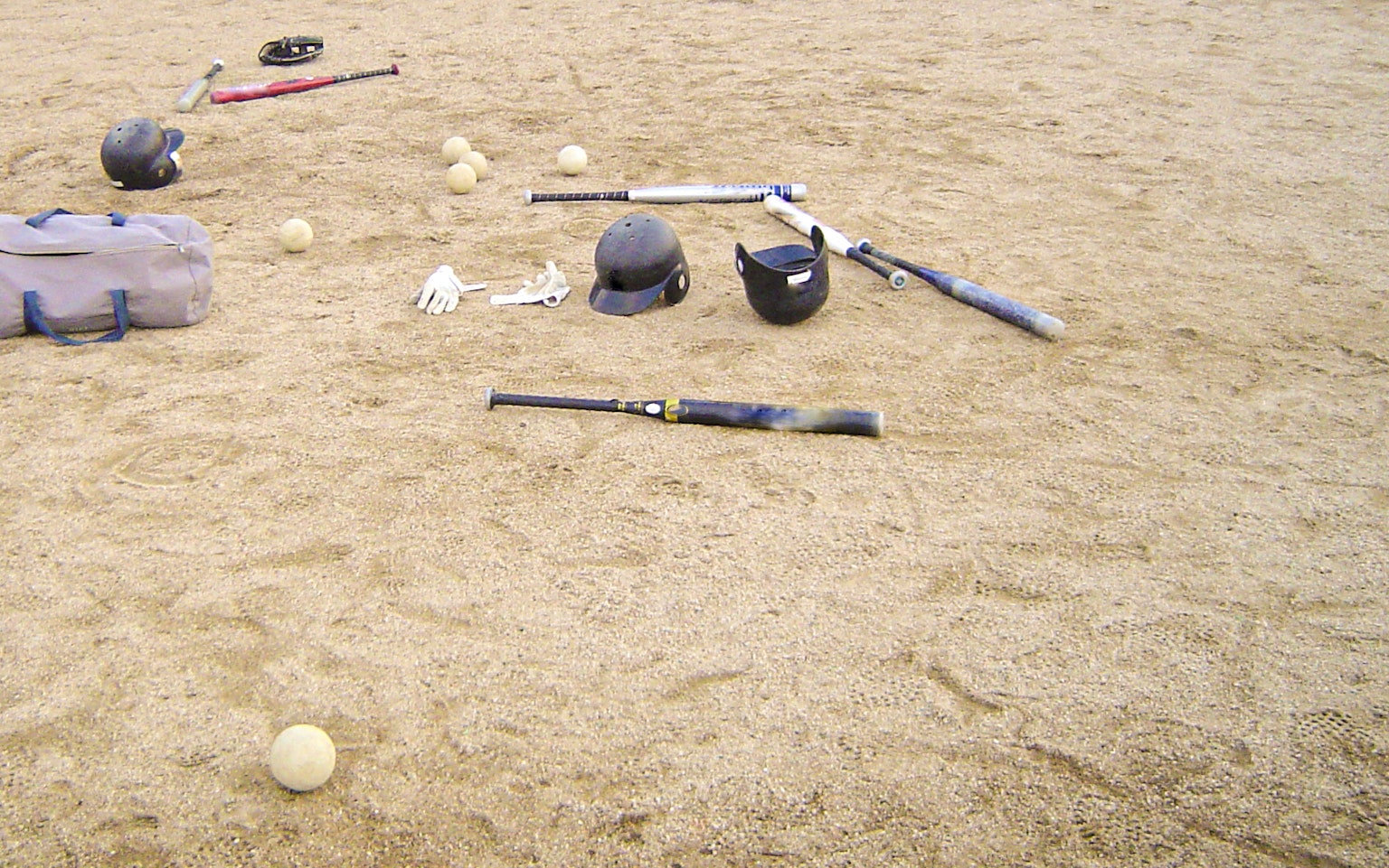 Attrezzatura da baseball e palline sparse sulla sabbia