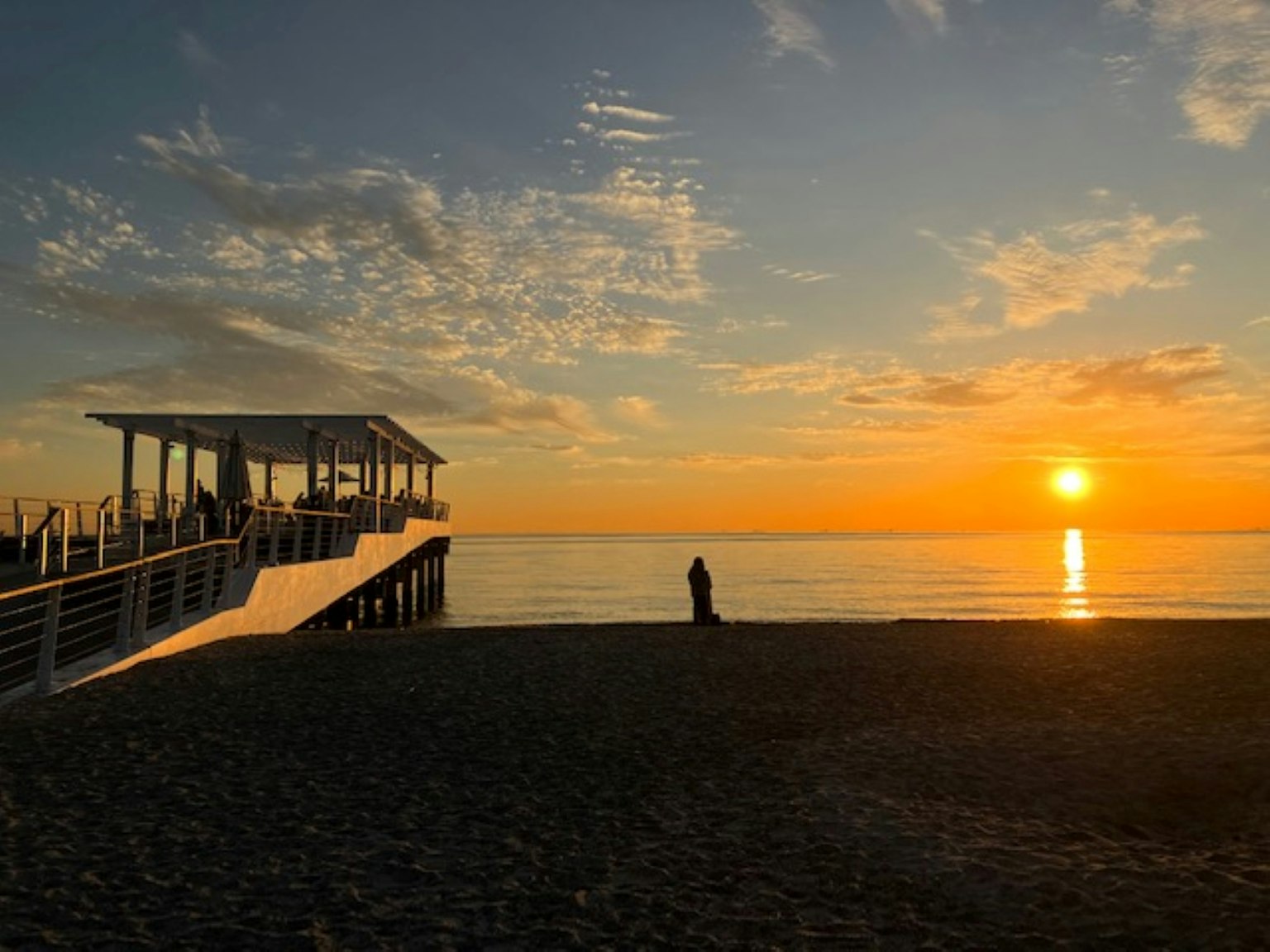 Scène de plage au coucher du soleil avec un quai et des silhouettes