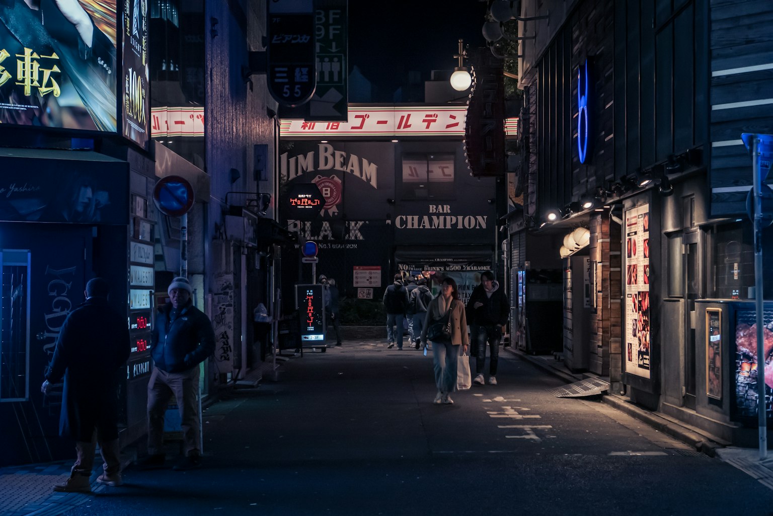 ภาพถนนมืดที่มีผู้คนเดินอยู่ภายใต้ป้ายไฟนีออนในเวลากลางคืน