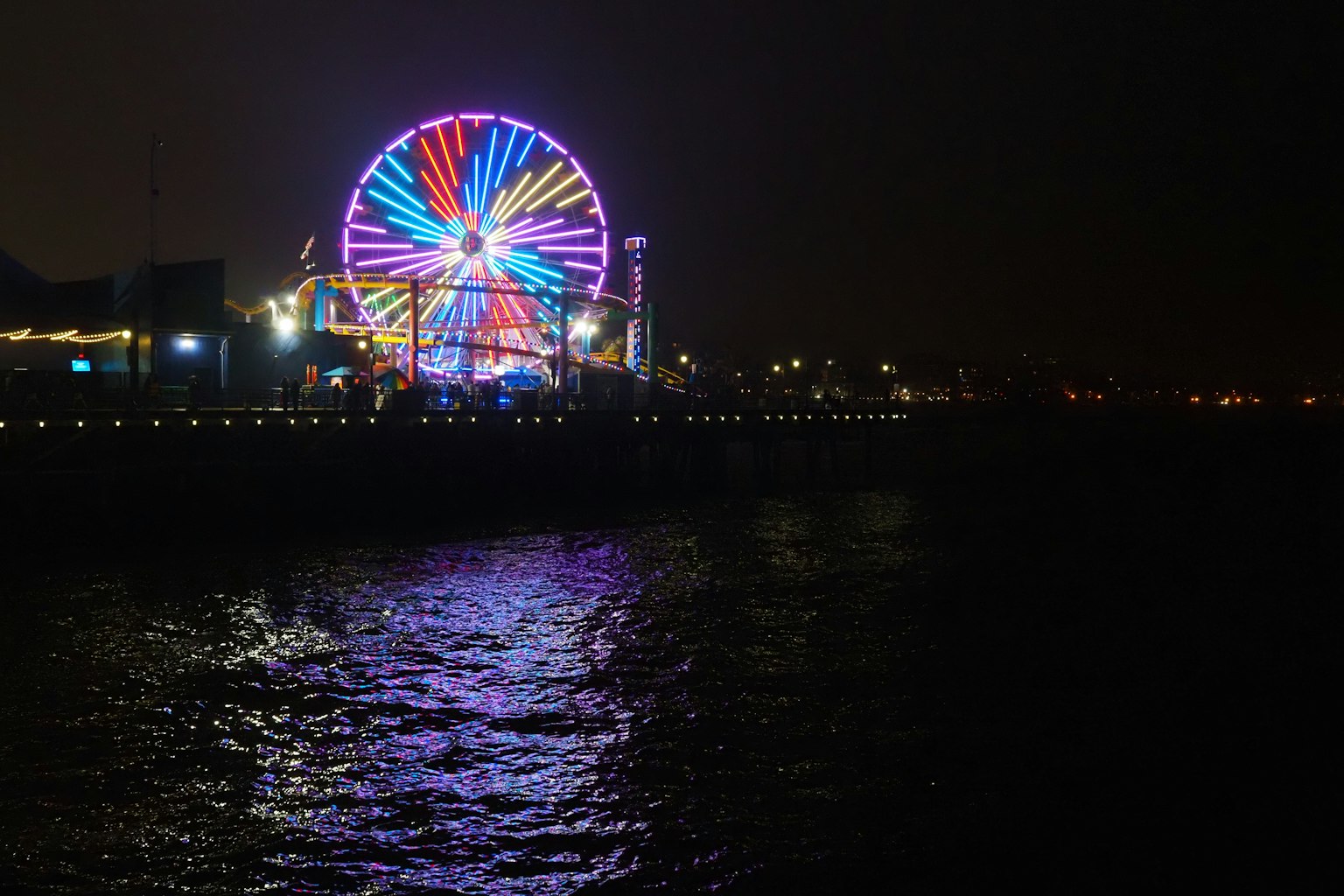 Grande roue colorée illuminée la nuit au bord de la mer