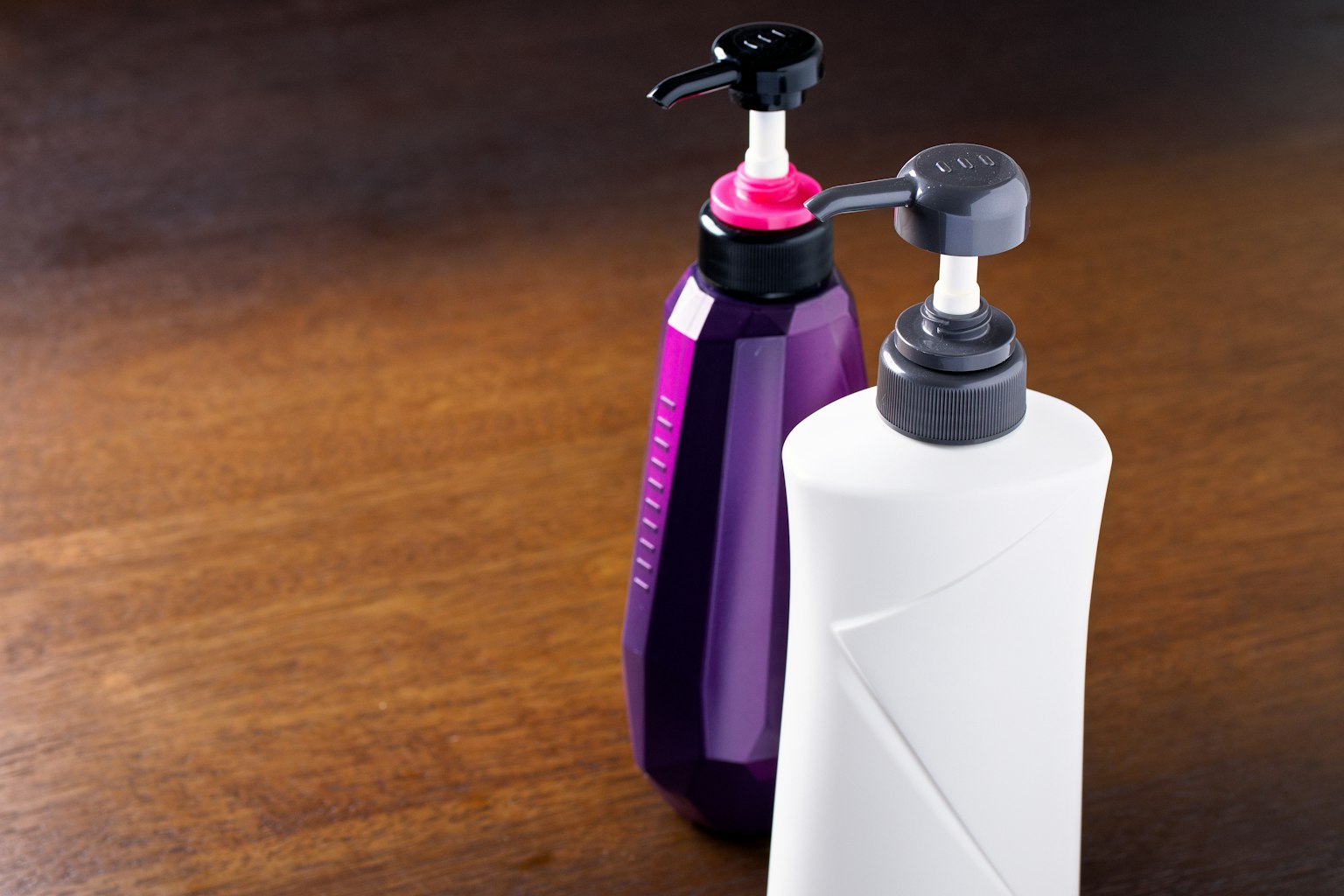 Botellas de bomba morada y blanca posicionadas sobre una mesa de madera