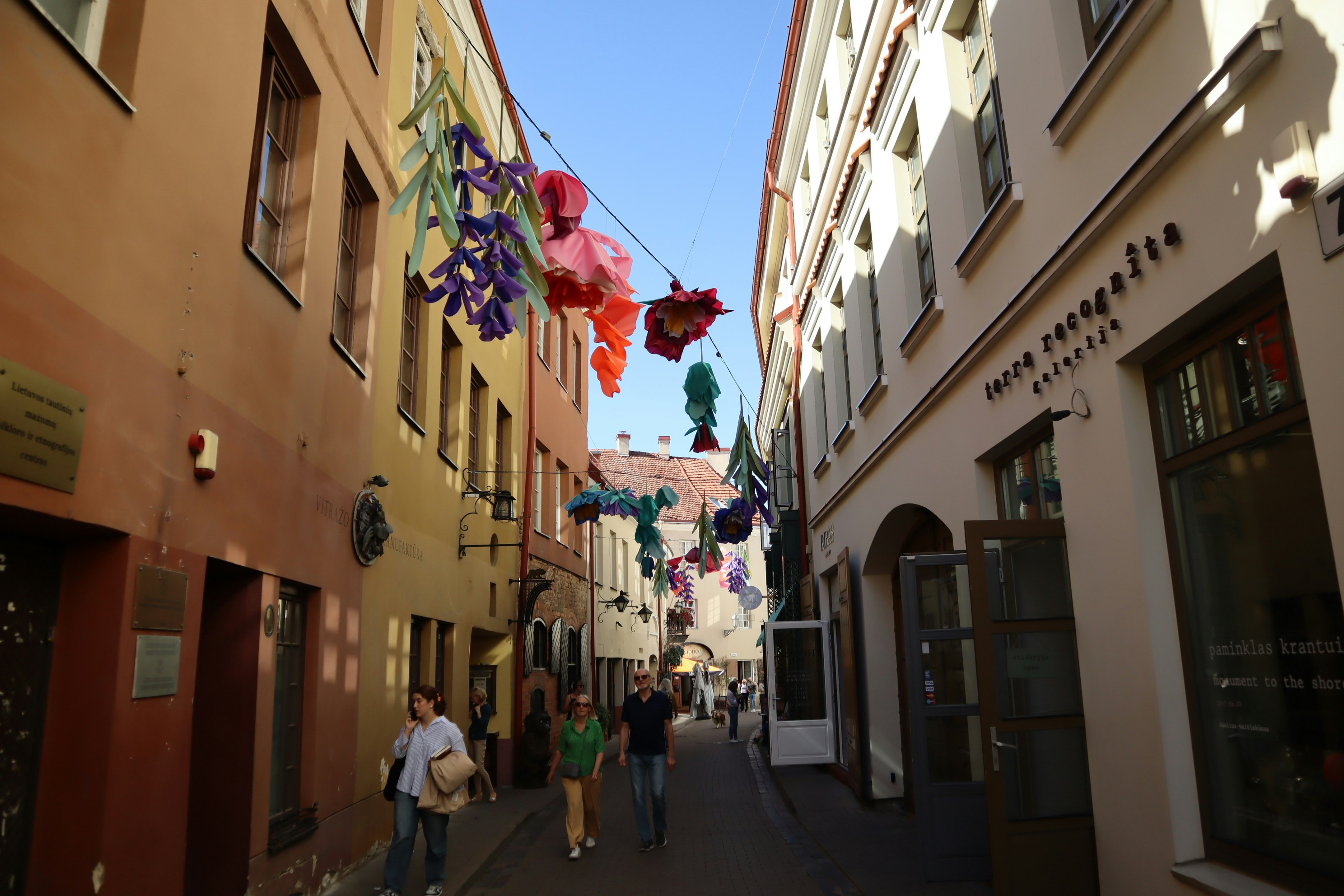 narrow alley with colorful hanging flags and storefront buildings