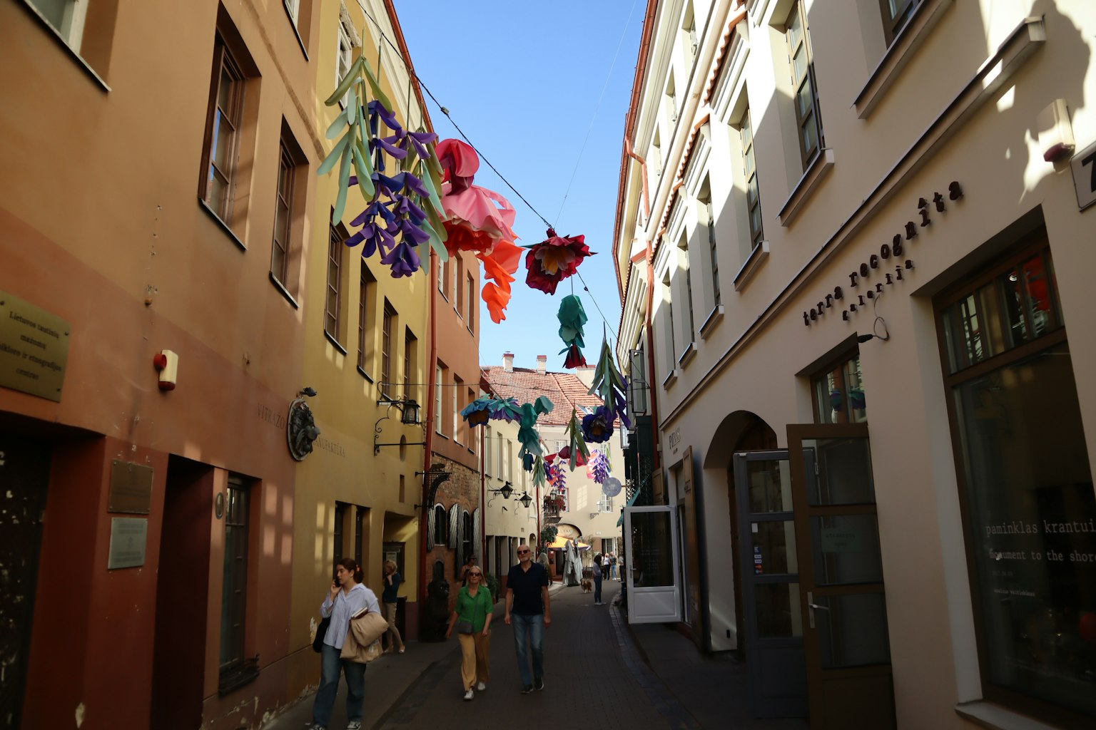 Colorful street decorated with hanging flowers and people walking