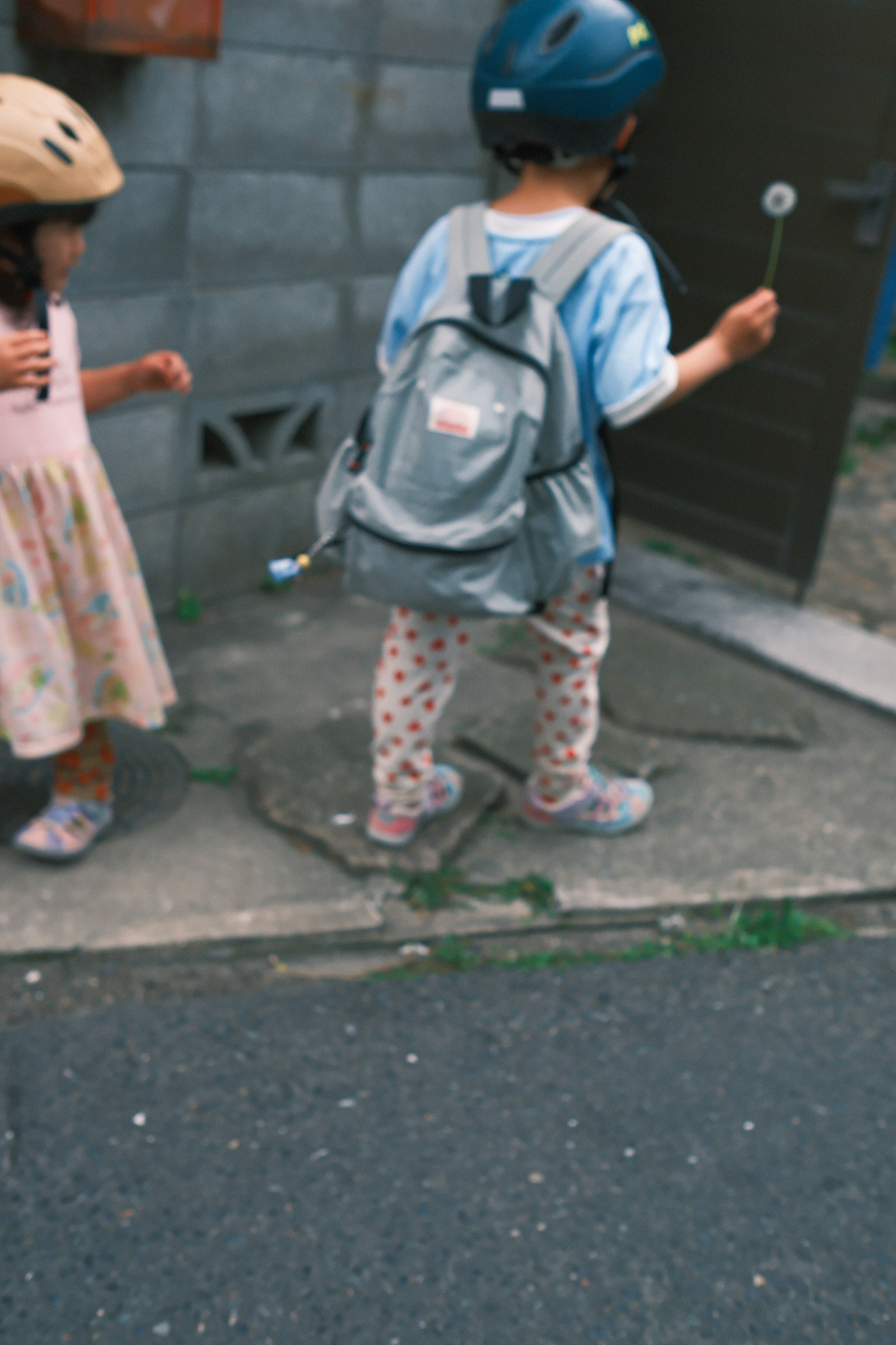 Due bambini che indossano caschi camminano su un marciapiede un ragazzo con uno zaino e una ragazza in un vestito