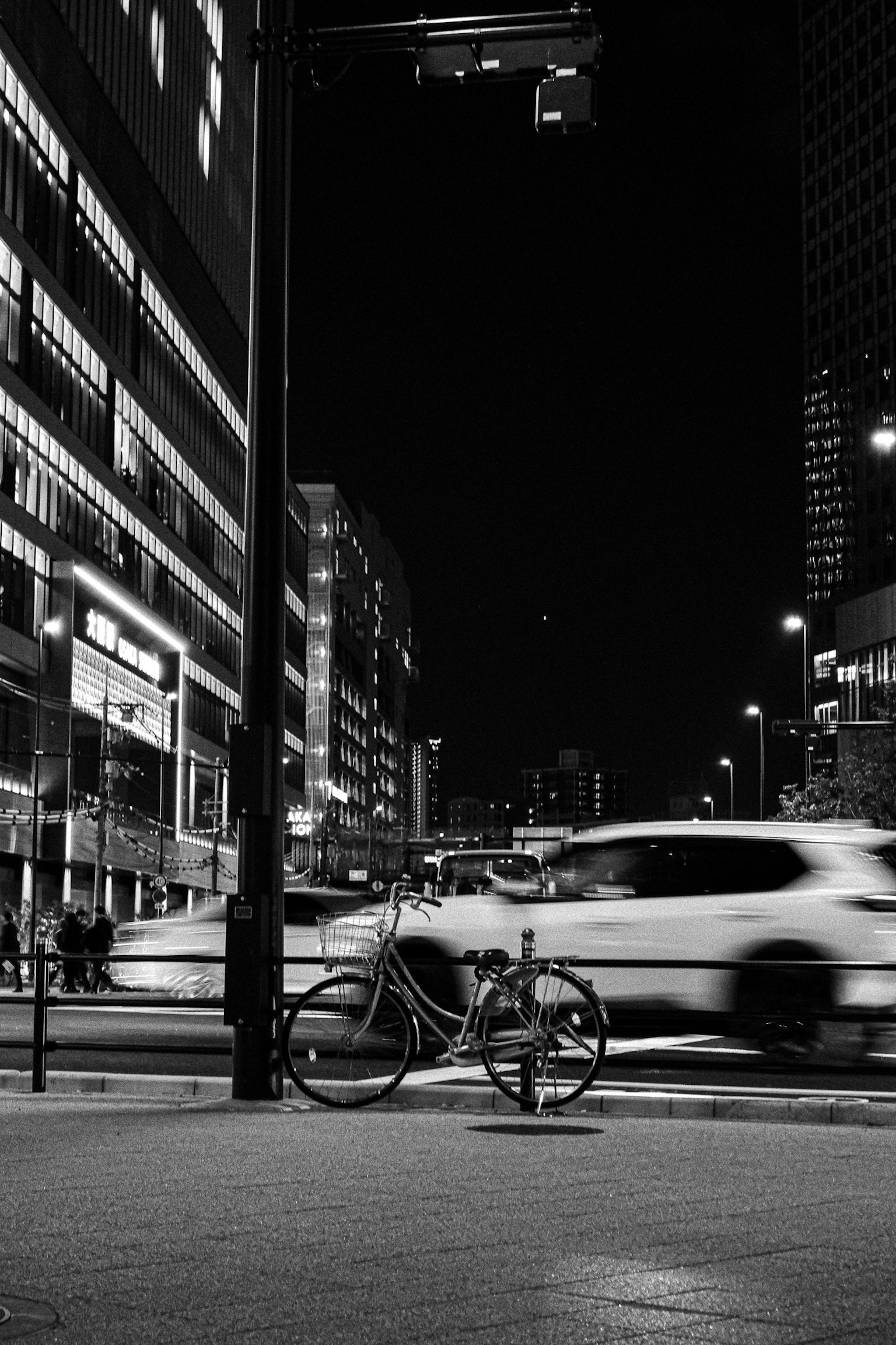 Night cityscape featuring a bicycle and blurred cars