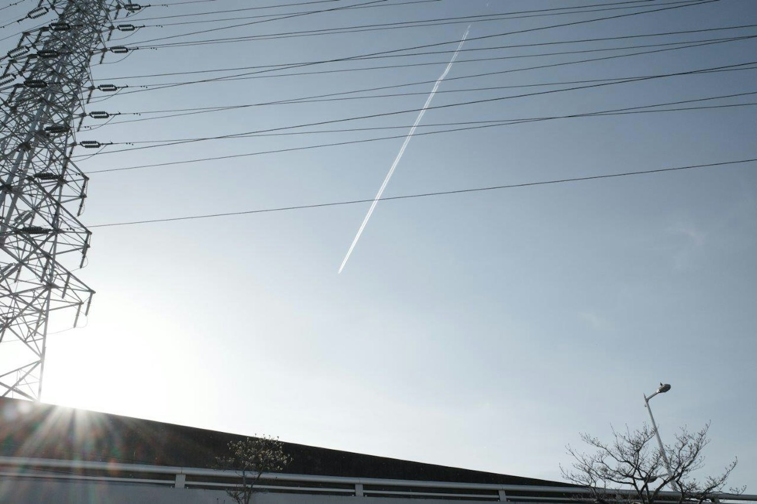 Clear sky with power lines and a contrail