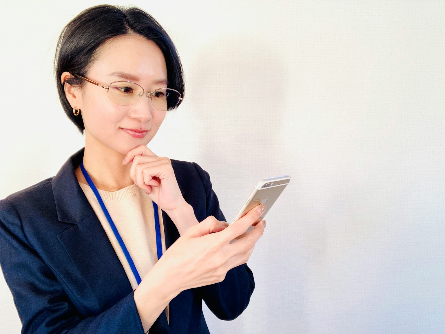 Una donna in giacca che tiene in mano uno smartphone pensierosa