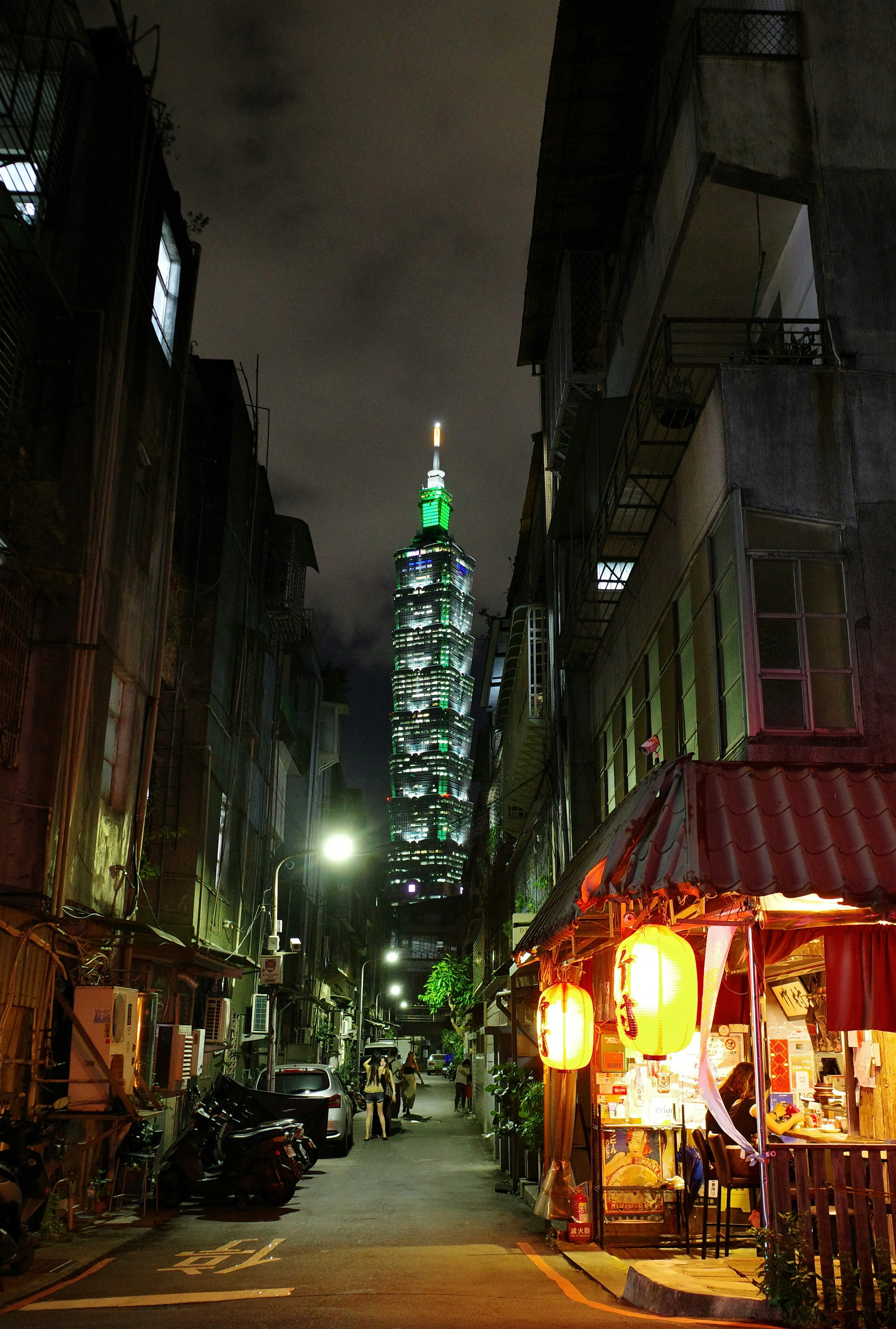 台北の路地に並ぶ屋台と夜景の高層ビル