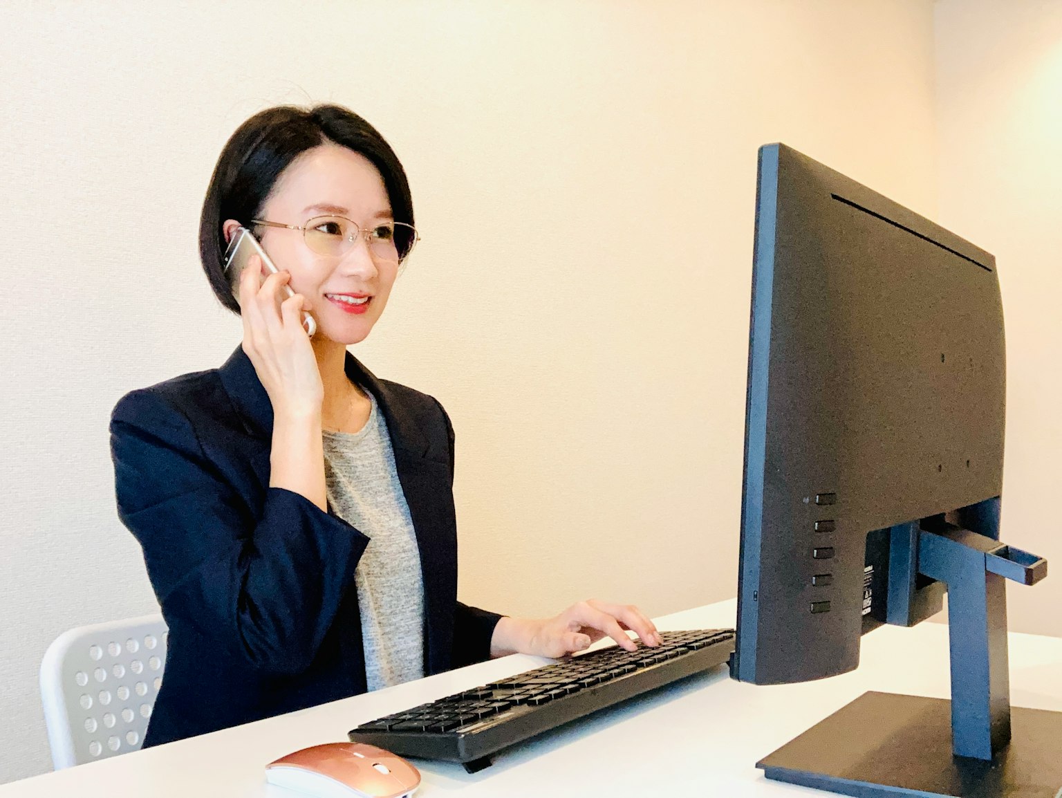 전화로 이야기하며 컴퓨터에서 작업하는 비즈니스 여성