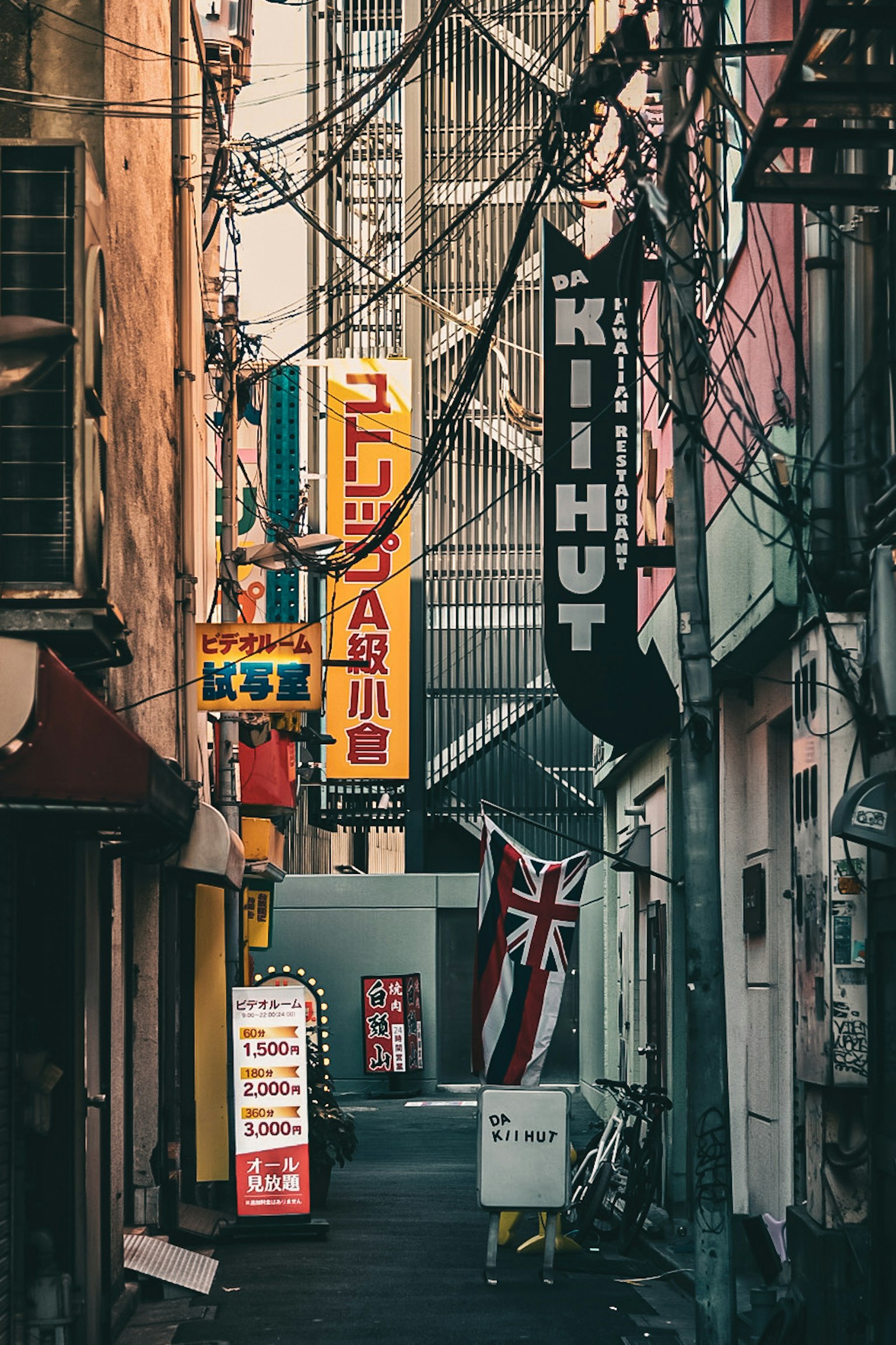 狭い路地に並ぶカラフルな看板とイギリスの国旗が見える