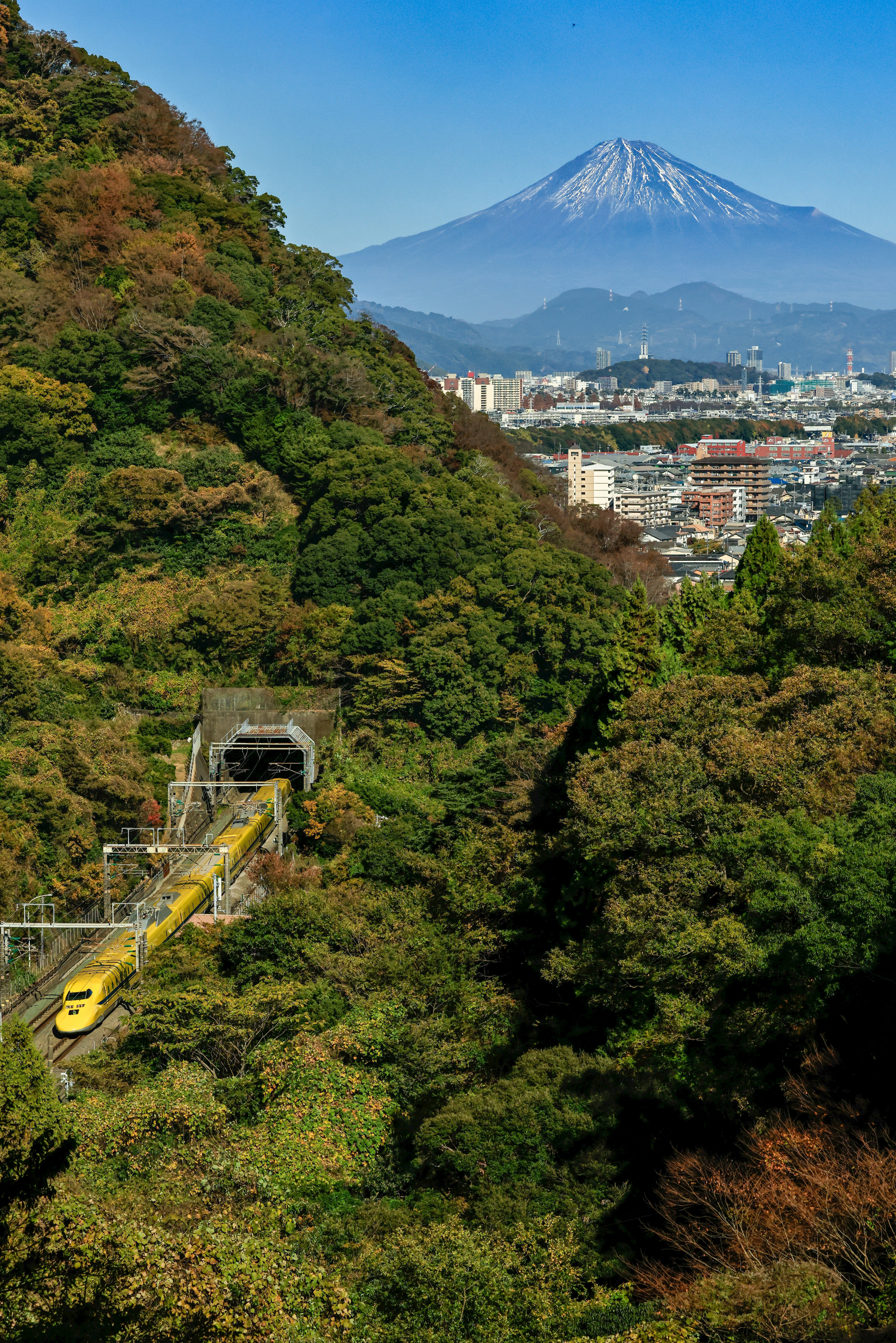 ドクターイエローと雲一つない富士山を望む山並みの景色