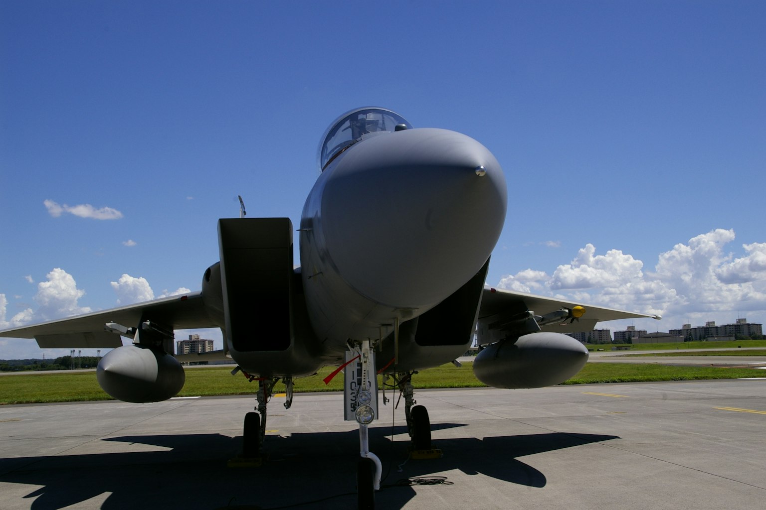 Vista frontal de un caza F-15 con cielo azul y nubes blancas