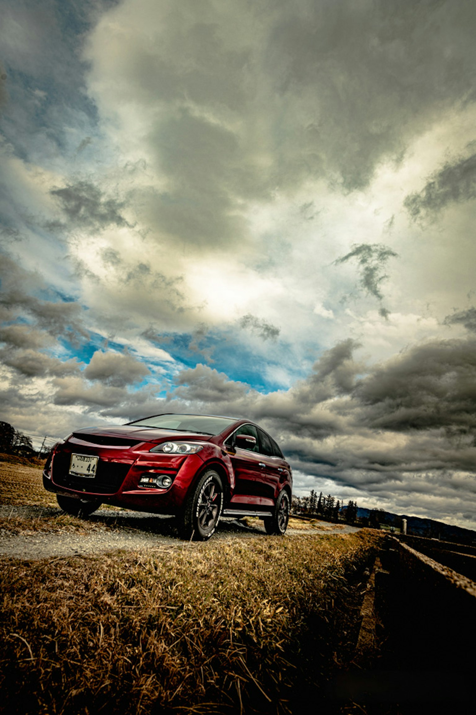 SUV rouge garé sous un ciel nuageux