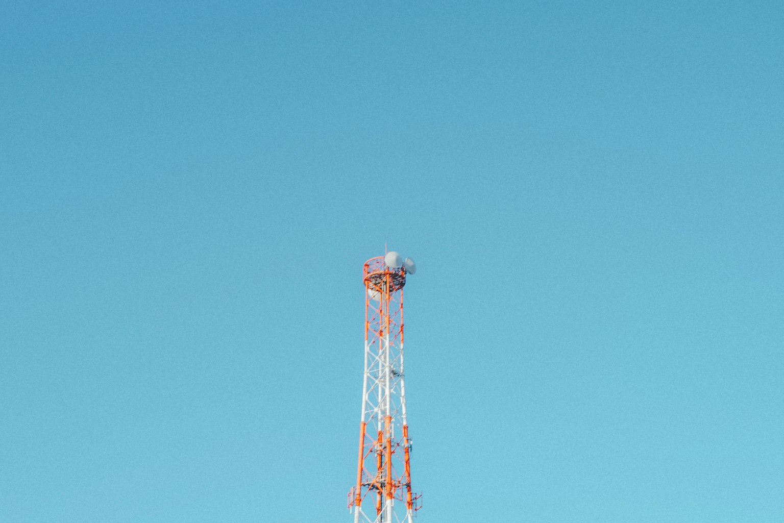 Tour de communication rouge et blanche contre un ciel bleu